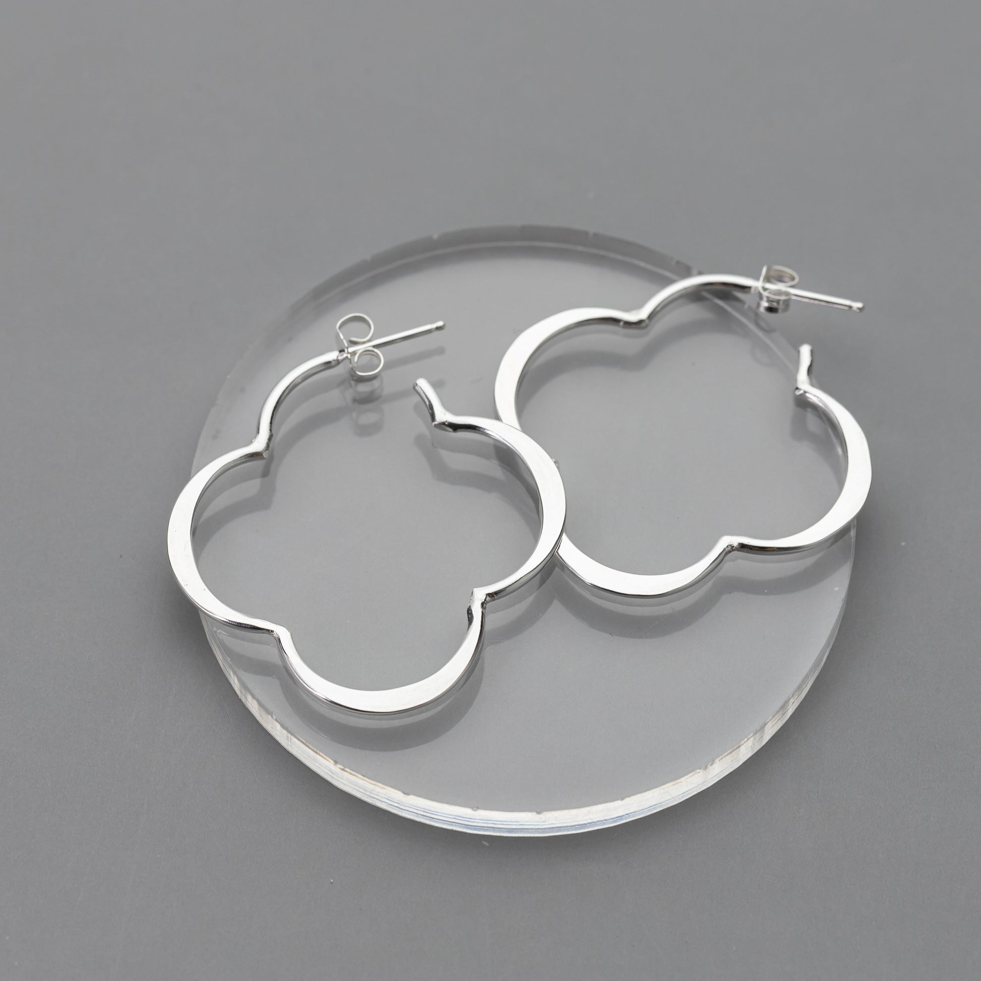 sterling Silver clover-shaped earrings on a gray background.  The earrings have post backs and secure ear nuts