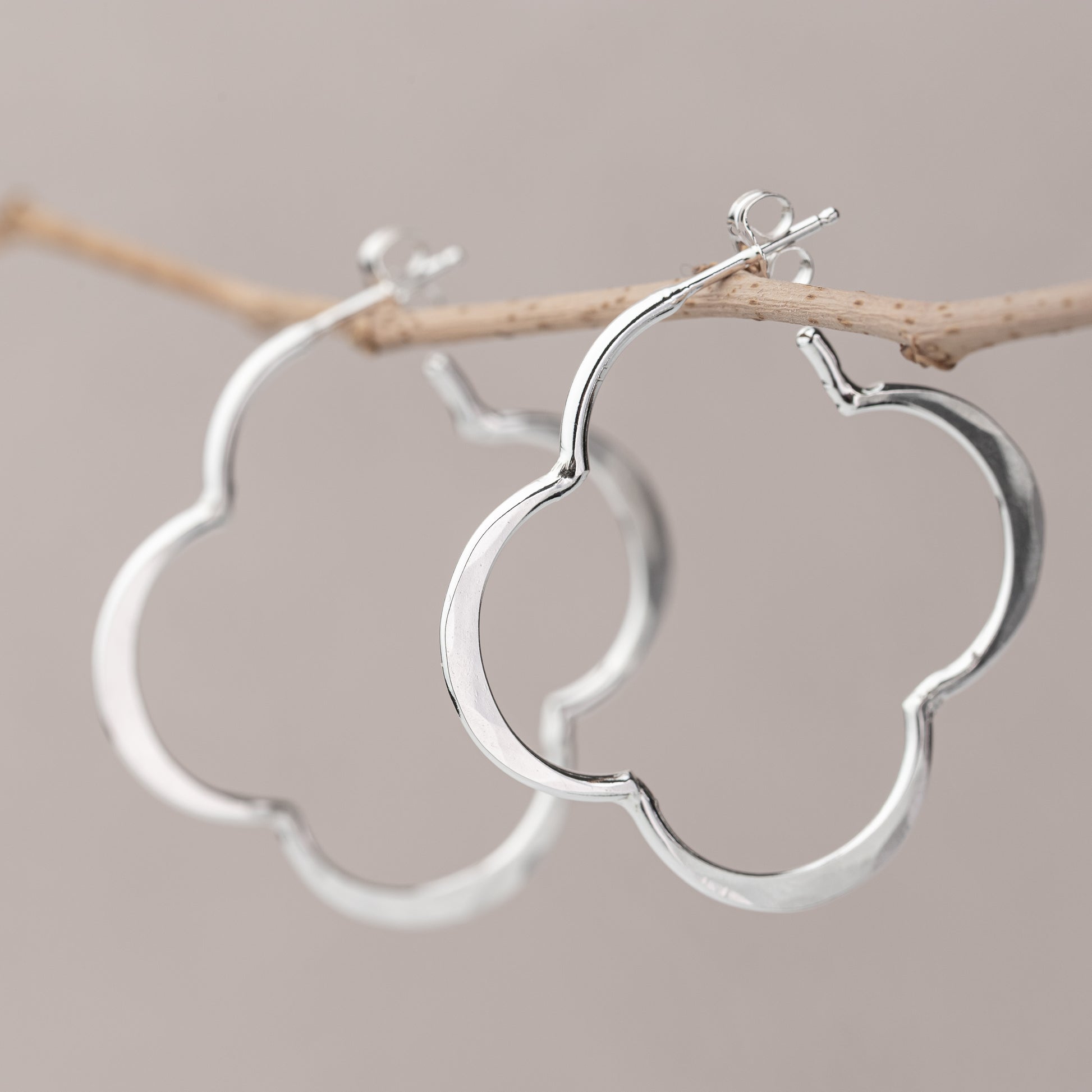unique handmade sterling Silver hoop earrings on a branch against a neutral background
