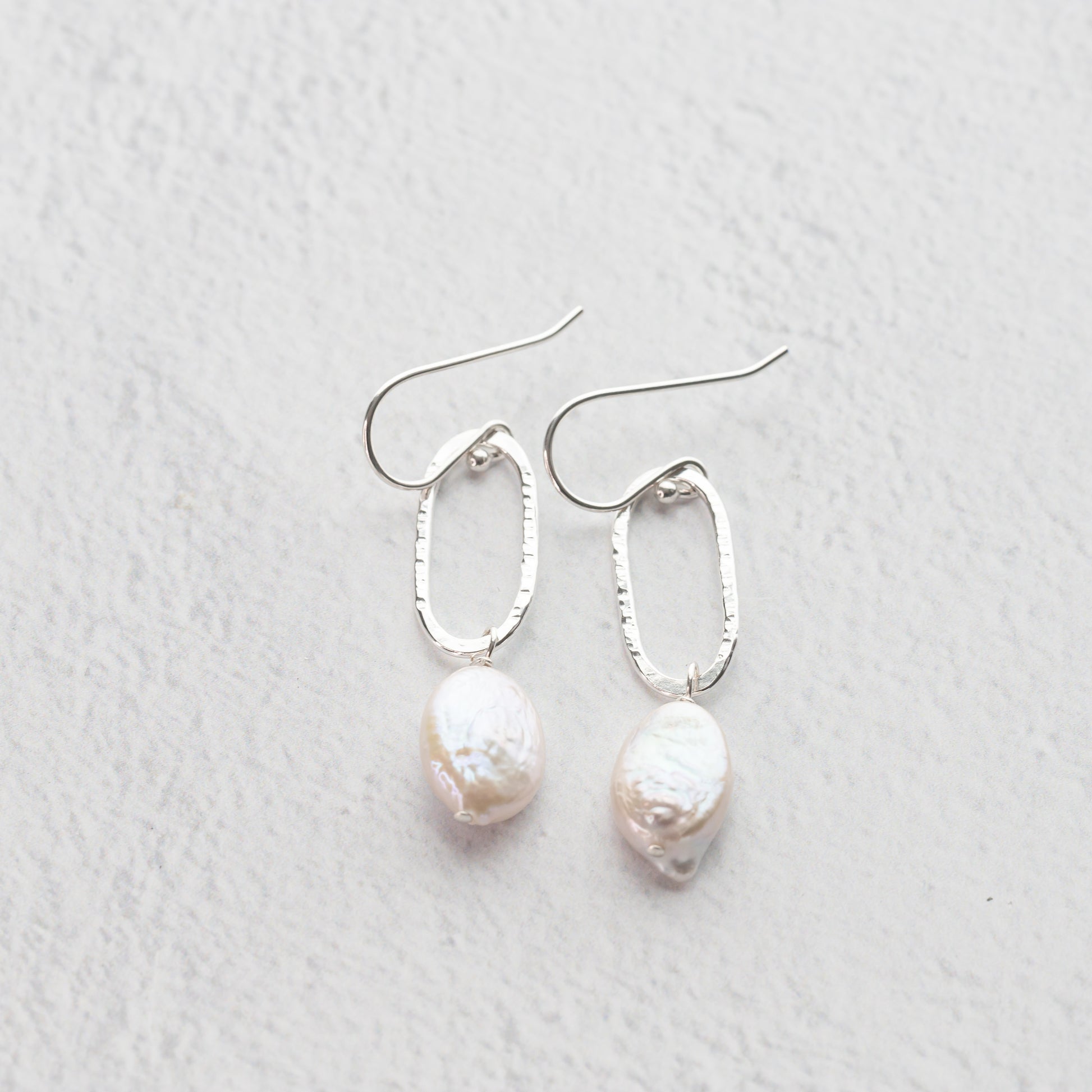handmade sterling silver and freshwater pearl earrings, hand hammered oval silver dangles drop from nickel free french hook ear wires with lustrous freshater pearl accents.