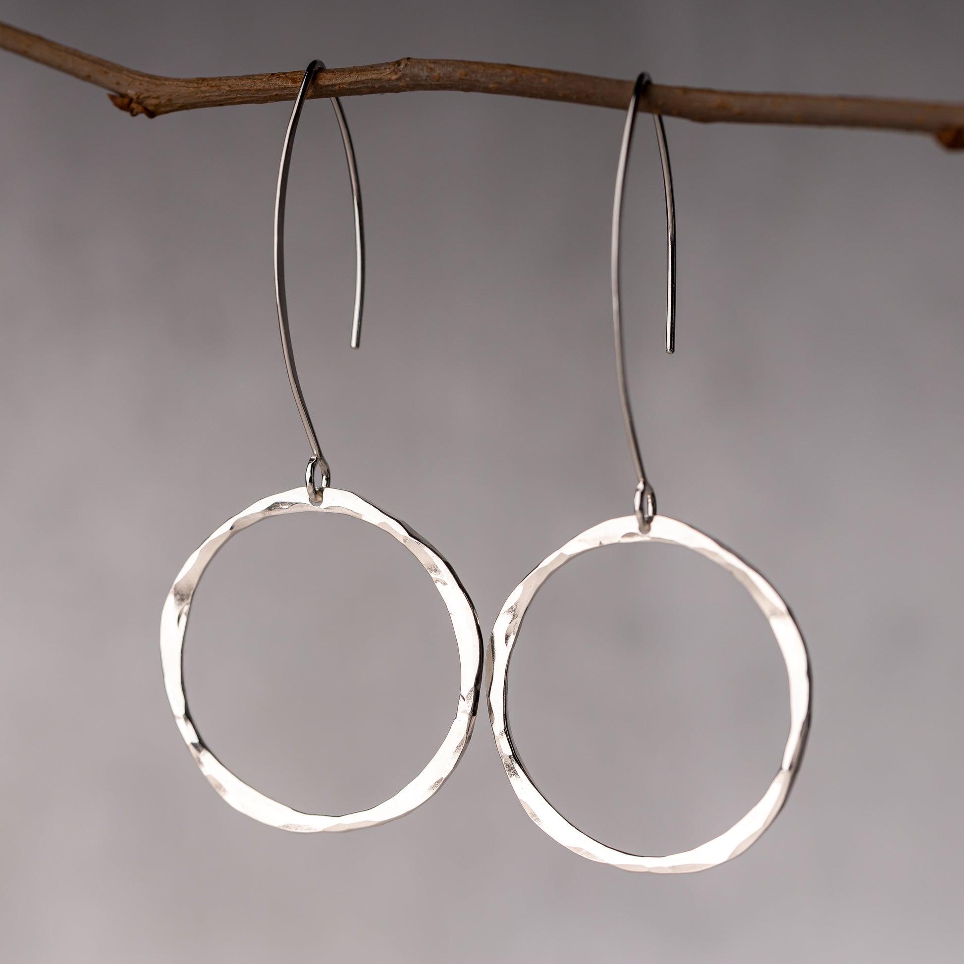 Long ear wire silver hoops shown hanging for scale