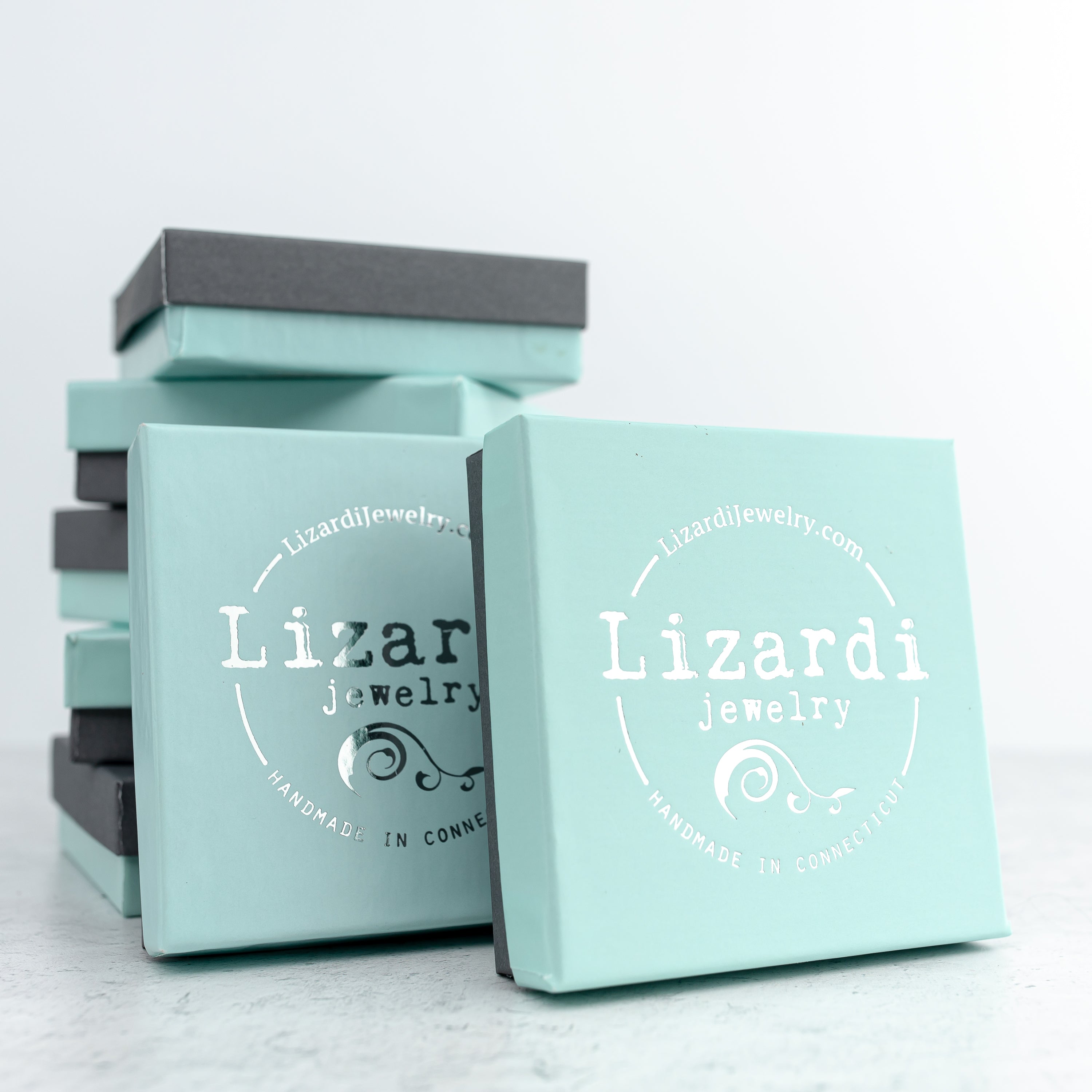 Light blue jewelry boxes with 'Lizardi Jewelry' branding on a light gray background