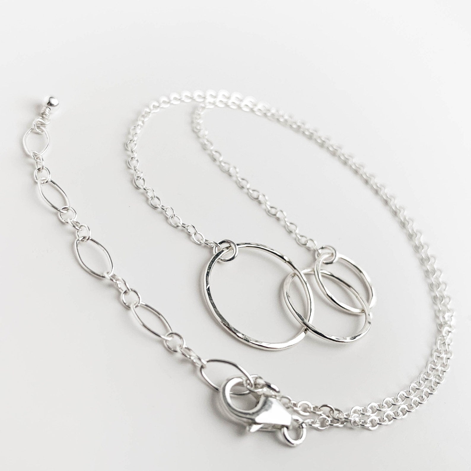 A sterling silver chain necklace with  interlocking rings, displayed on a clean white background.