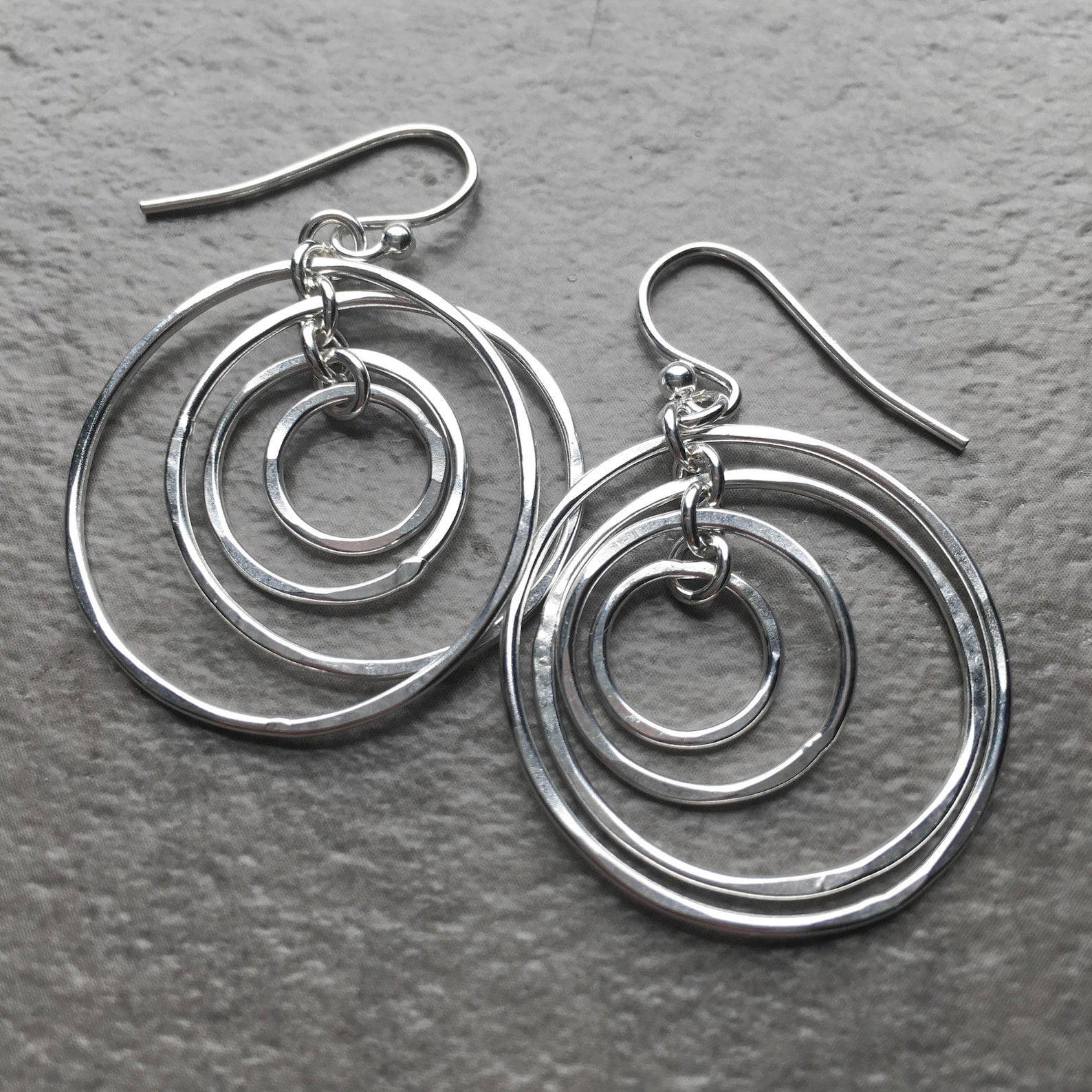 Silver hoop earrings on a gray surface