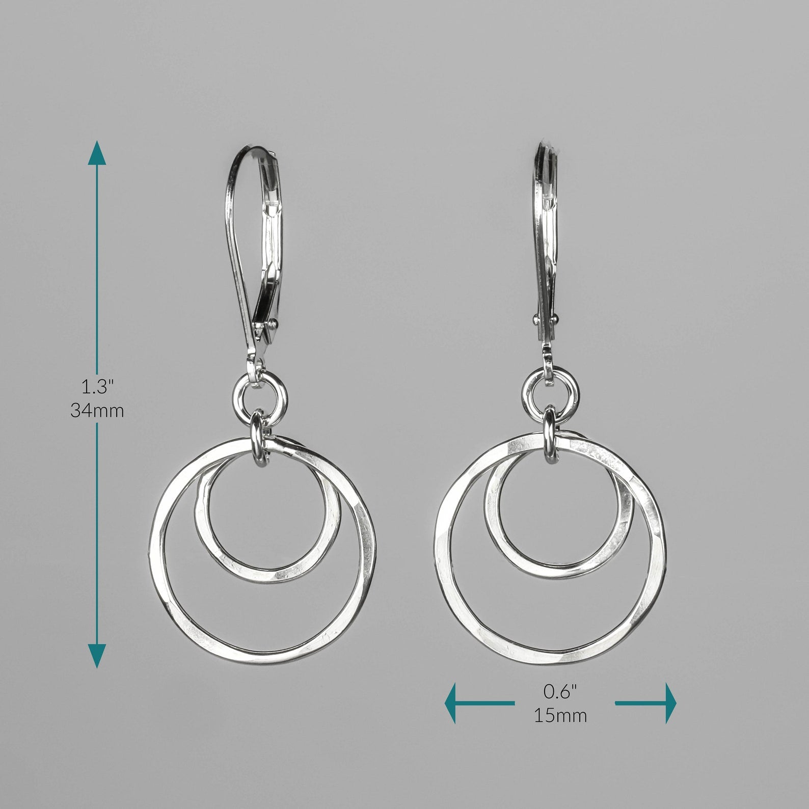 Silver double-ring hoop dangle earrings shown on a gray background with teal measurement arrows and text indicating 1.3 inches (34mm) height and 0.6 inches (15mm) width.