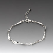 A polished sterling silver link bracelet with alternating flat polished bars and oval chain links, displayed on a dark gray gradient background.
