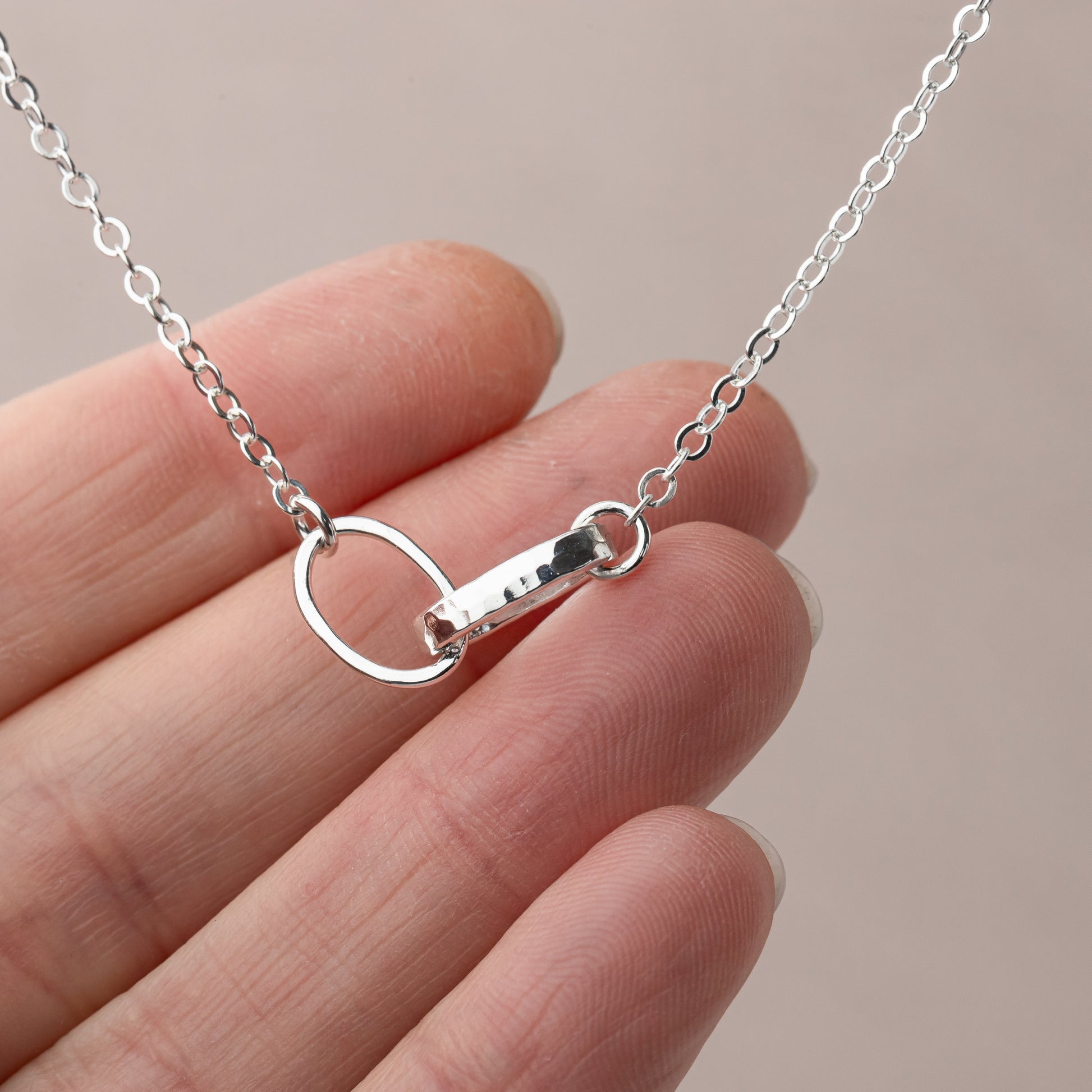 sterling silver thick and thin link necklace  held by a hand against a neutral background