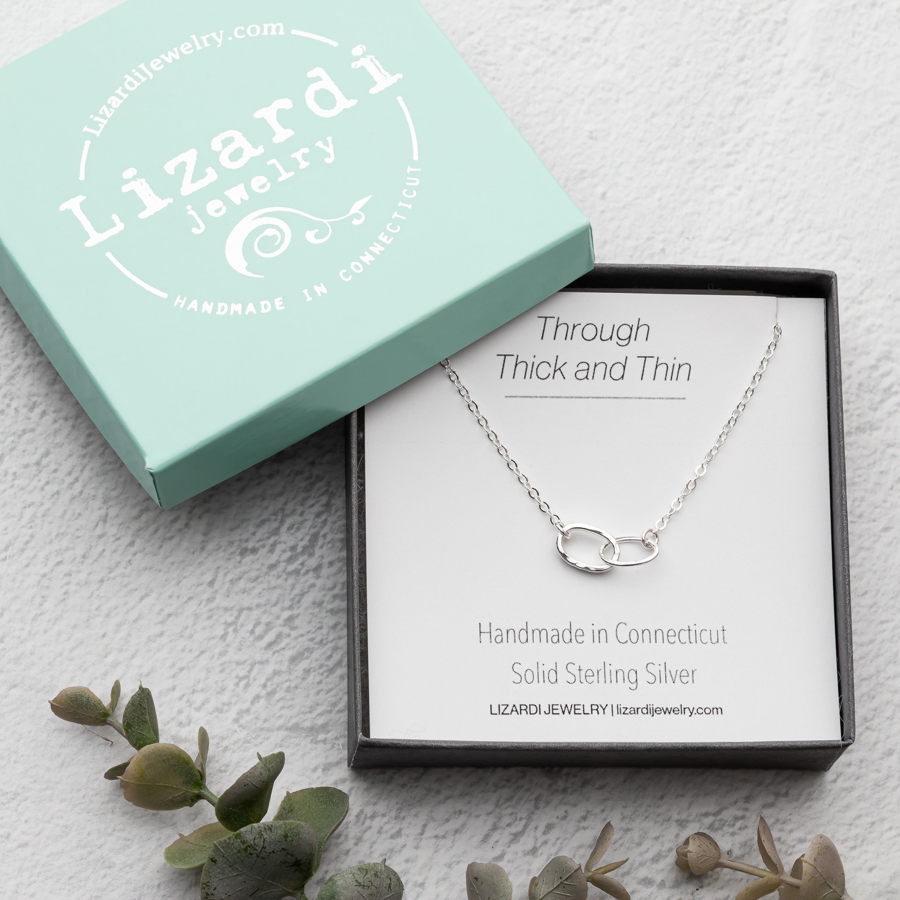 Handmade sterling silver  necklace in a Lizardi Jewelry box on a textured surface with greenery.  The perfect sentimental and thoughtful gift for her