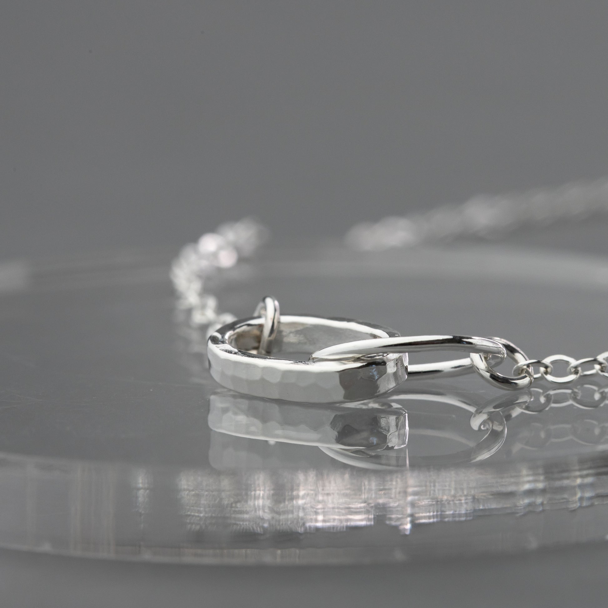 Thick and thin interlocked sterling silver necklace up close to show the hand hammered details in this handmade design.