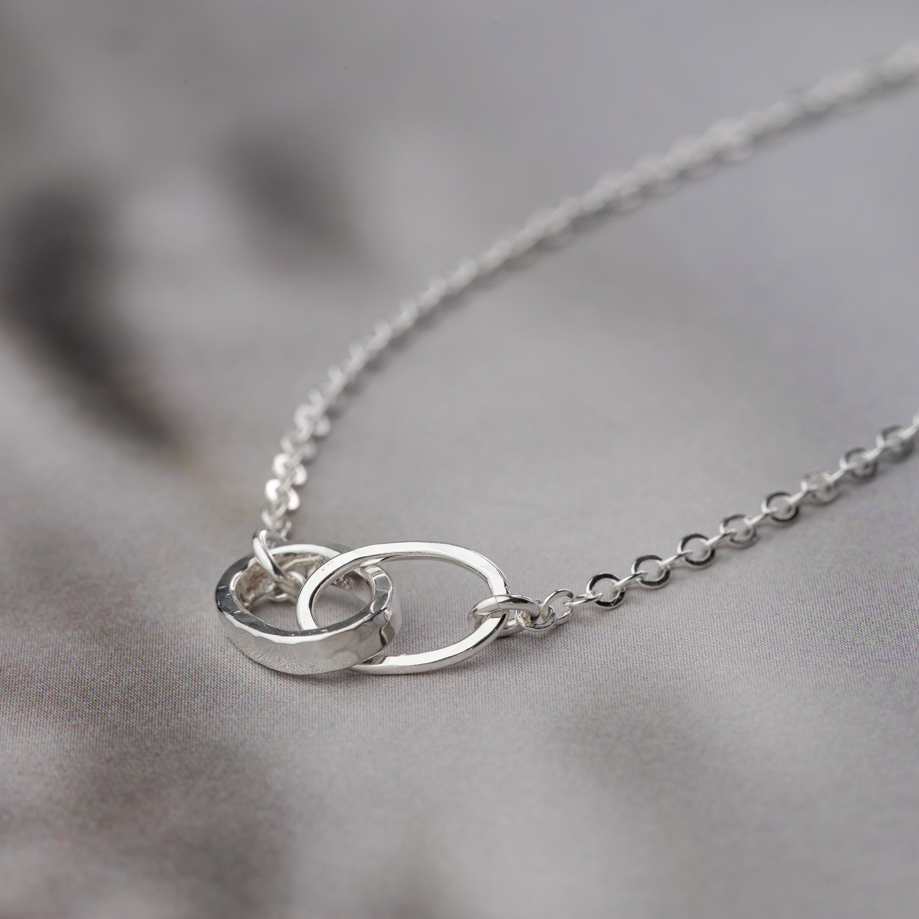 handmade sterling silver necklace with interlocking links on a soft gray background