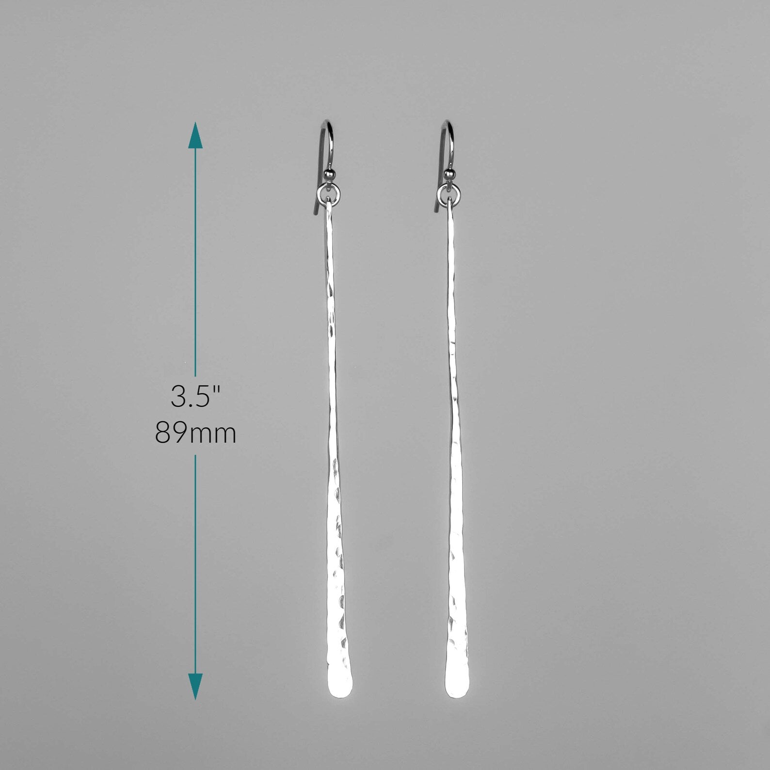 A pair of long silver drop earrings with a hammered texture, shown on a neutral gray background with a vertical measurement arrow indicating a height of 3.5 inches (89 mm). Handmade by Lizardi Jewelry 