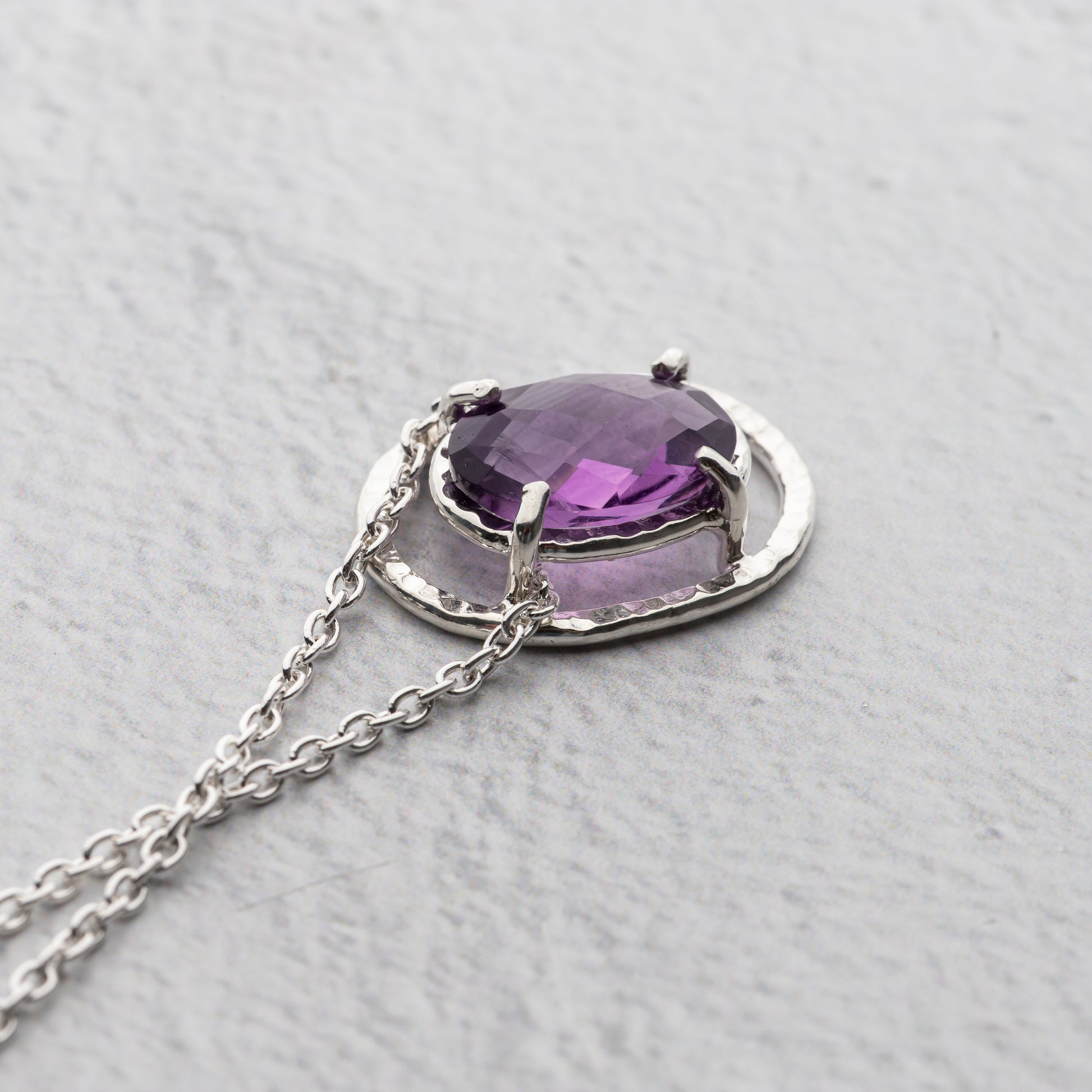 Necklace with a purple gemstone pendant on a light gray background