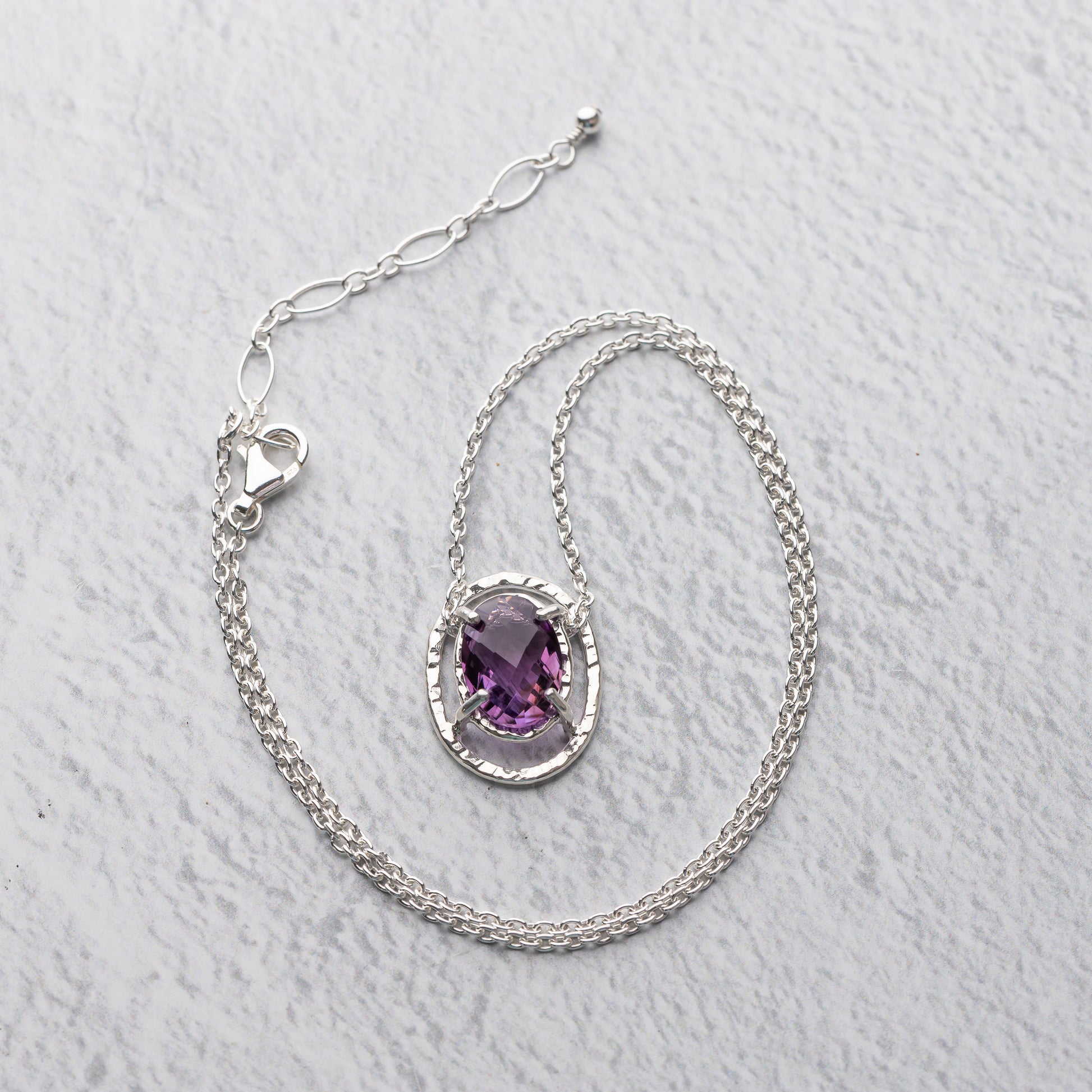 Sterling Silver necklace with a purple amethyst gemstone on a light gray background