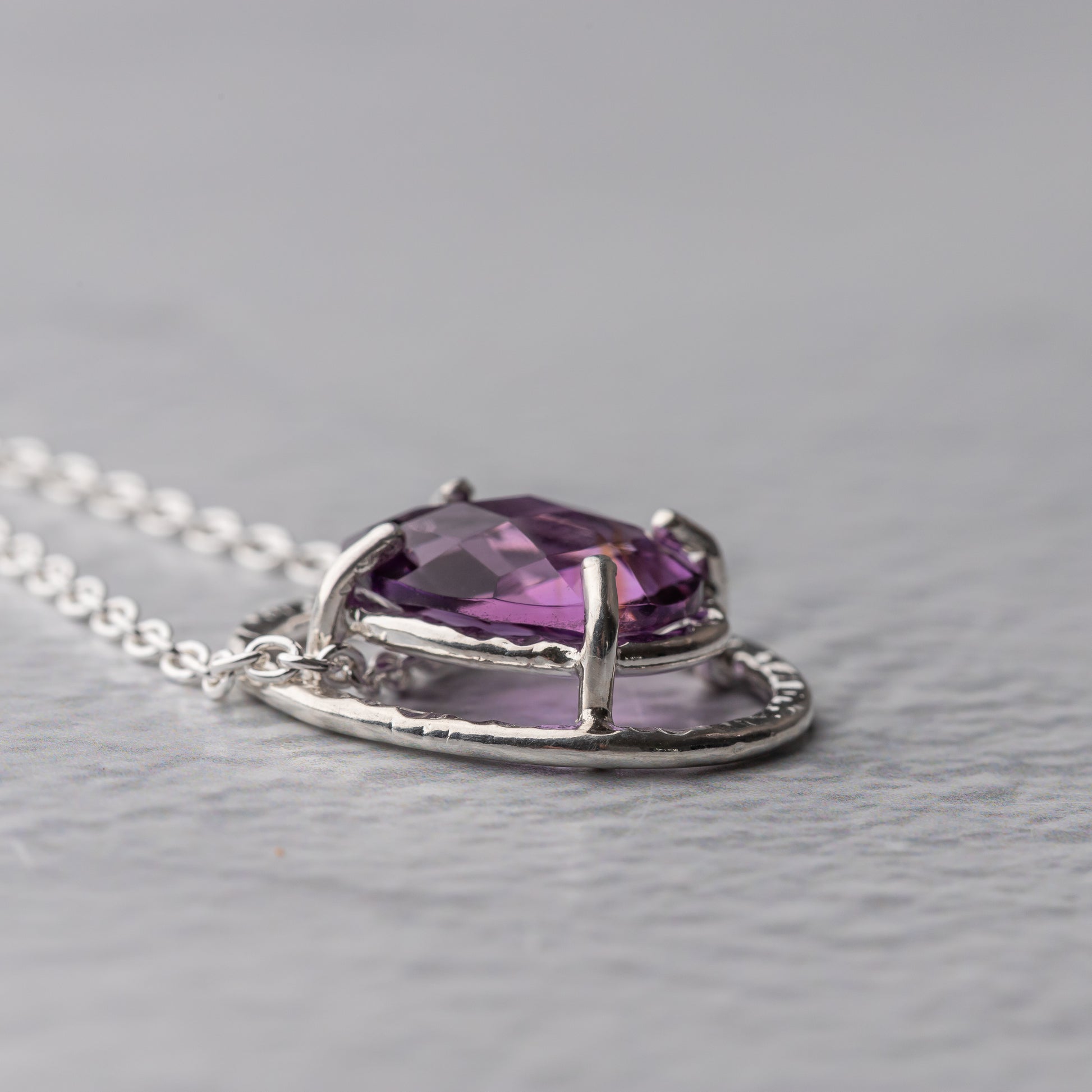 Purple amethyst gemstone necklace on a gray background