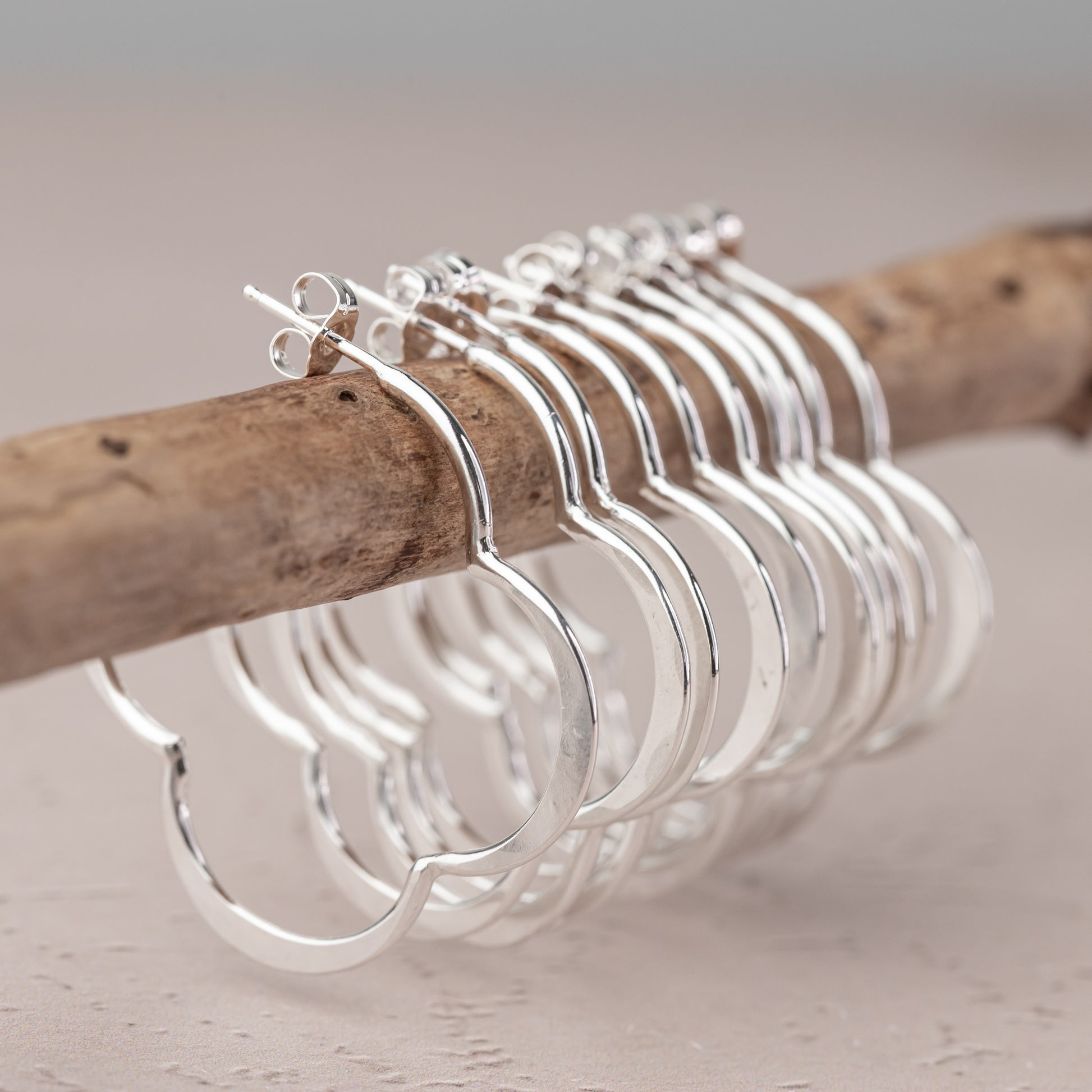 handmade sterling Silver hoop earrings on a wooden stick with a neutral background