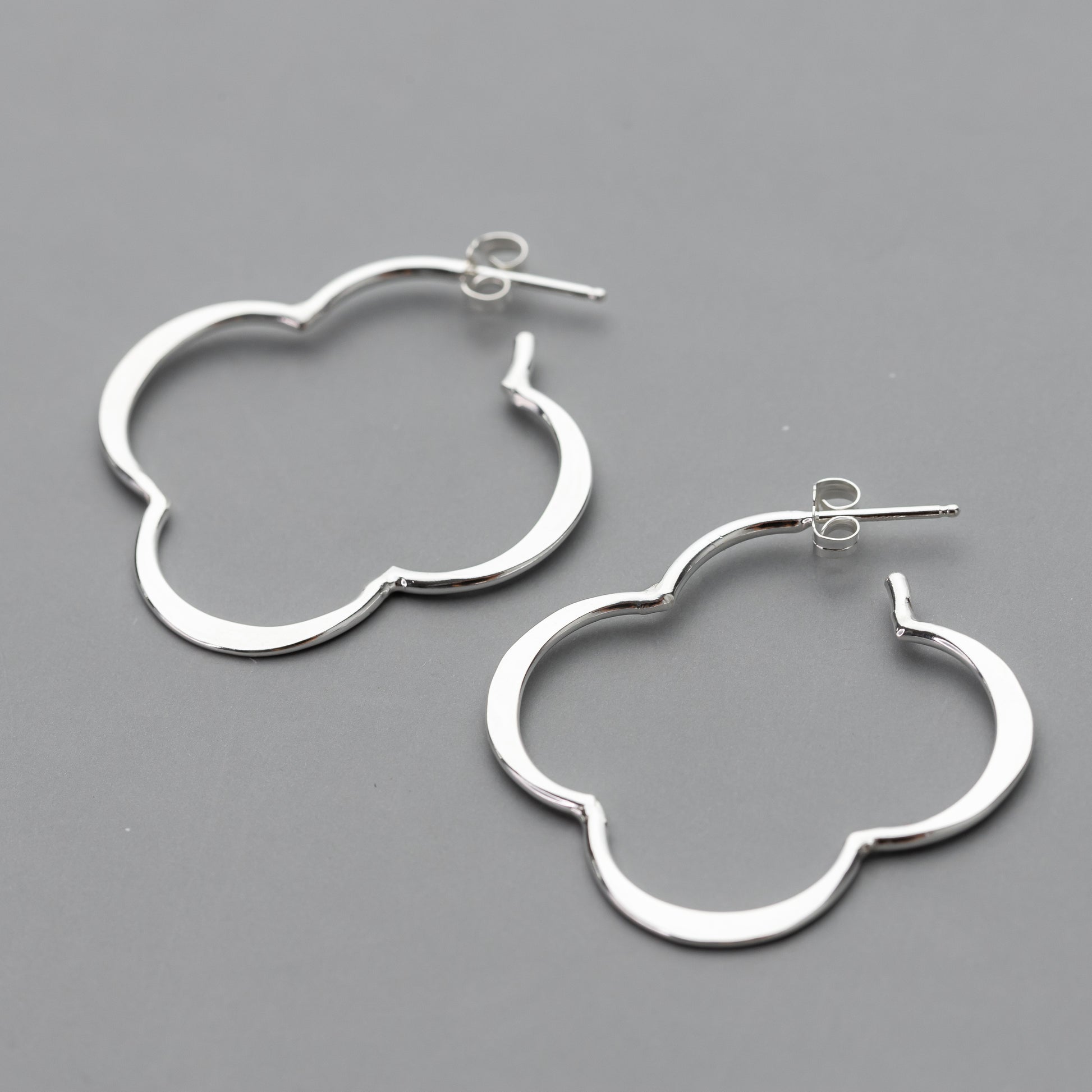 handmade sterling Silver quatrefoil hoop earrings on a gray background