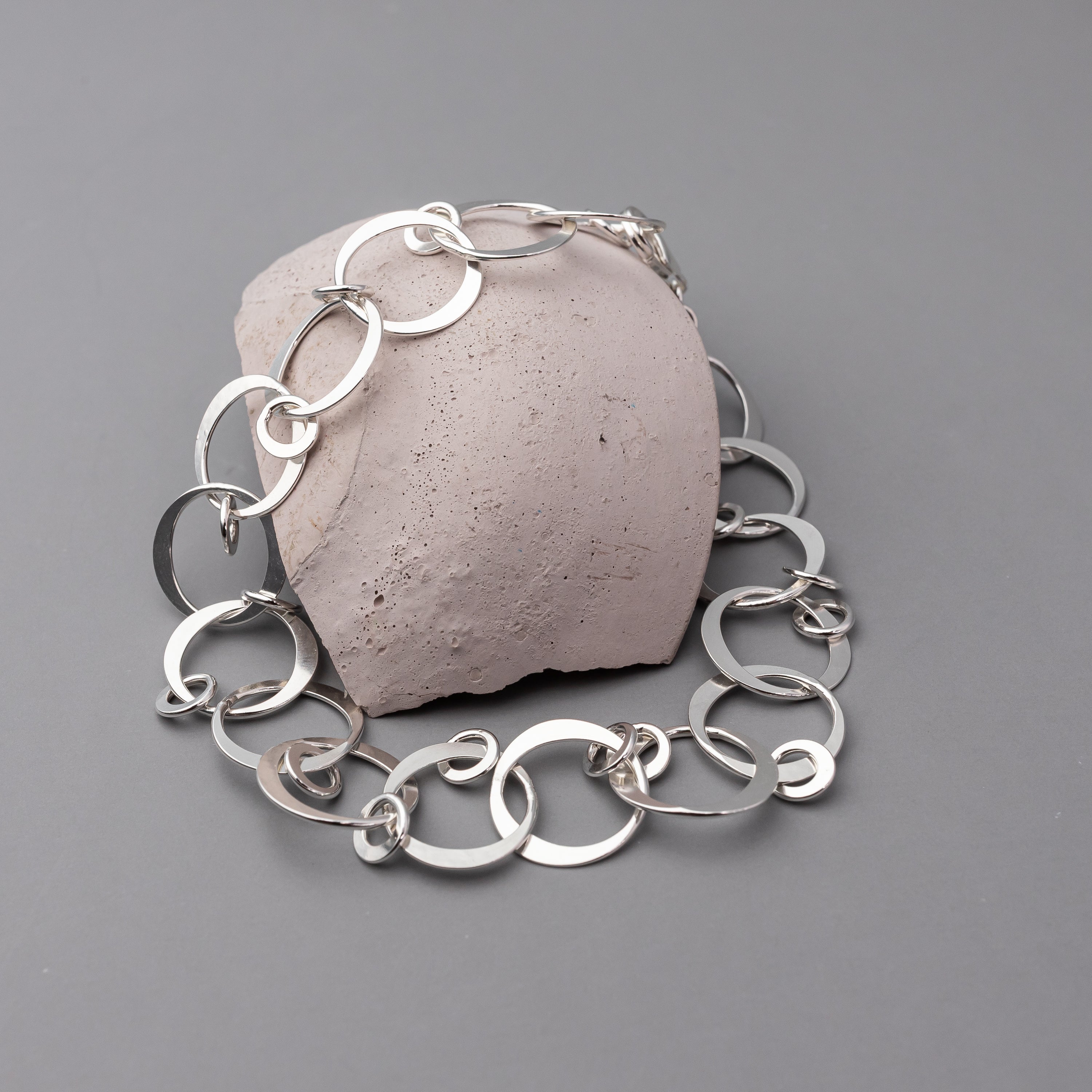 Hammered Sterling Silver chain bracelet on a textured stone against a gray background