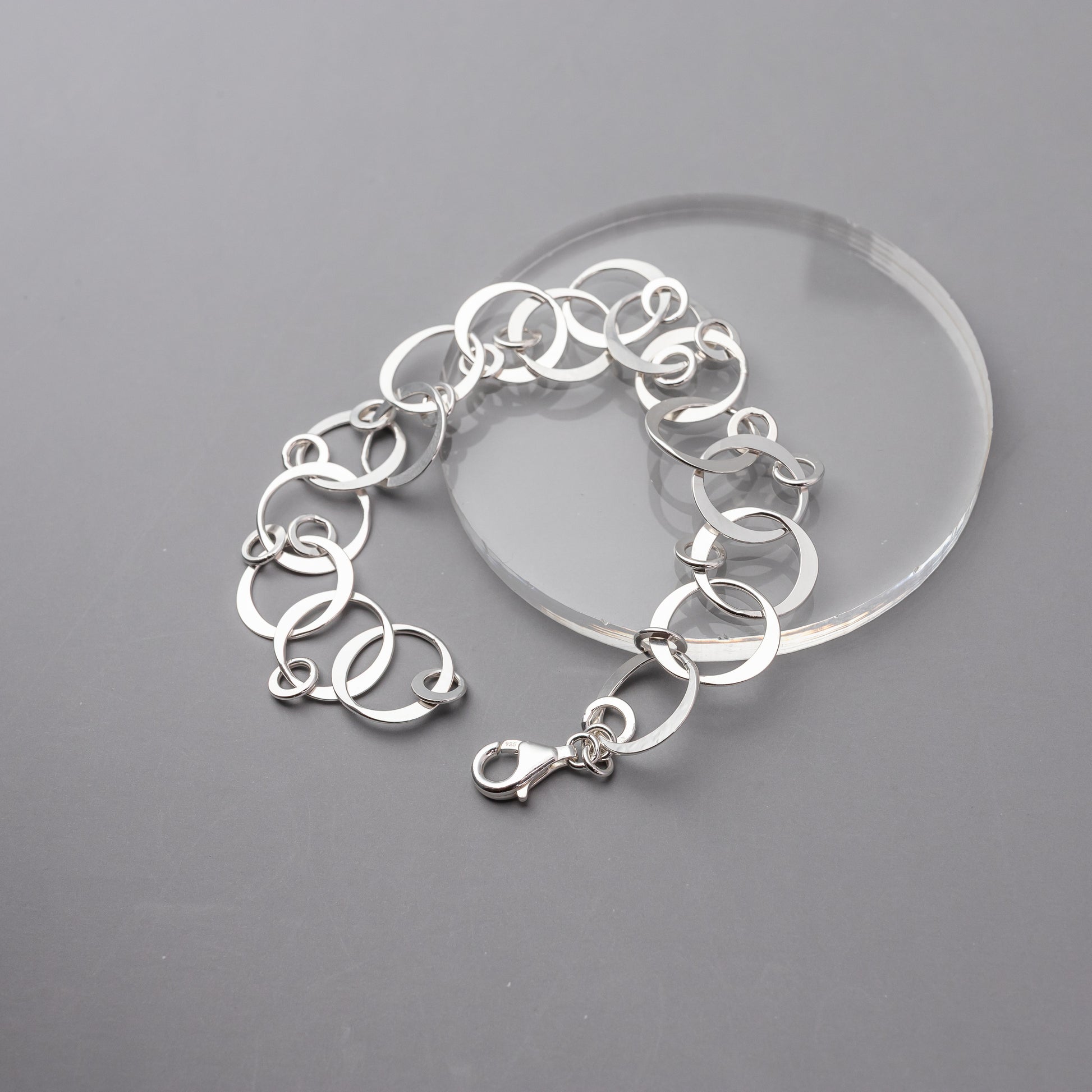 Sterling silver circles bracelet on a clear stand against a gray background