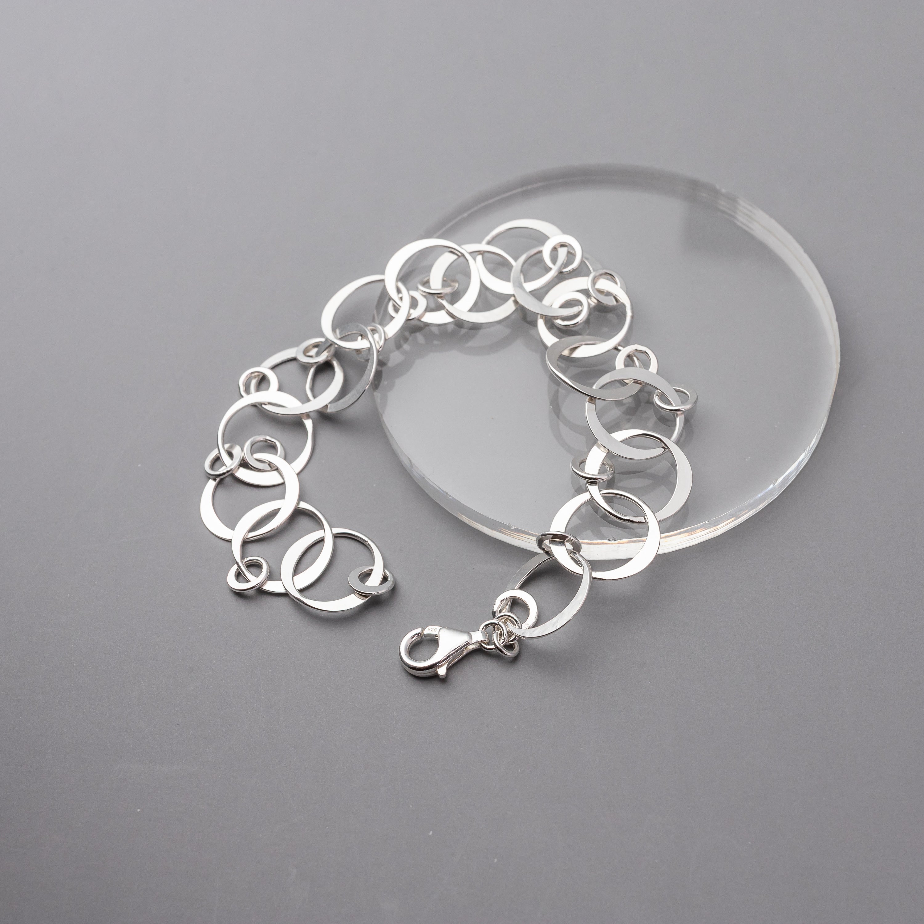 Sterling silver circles bracelet on a clear stand against a gray background