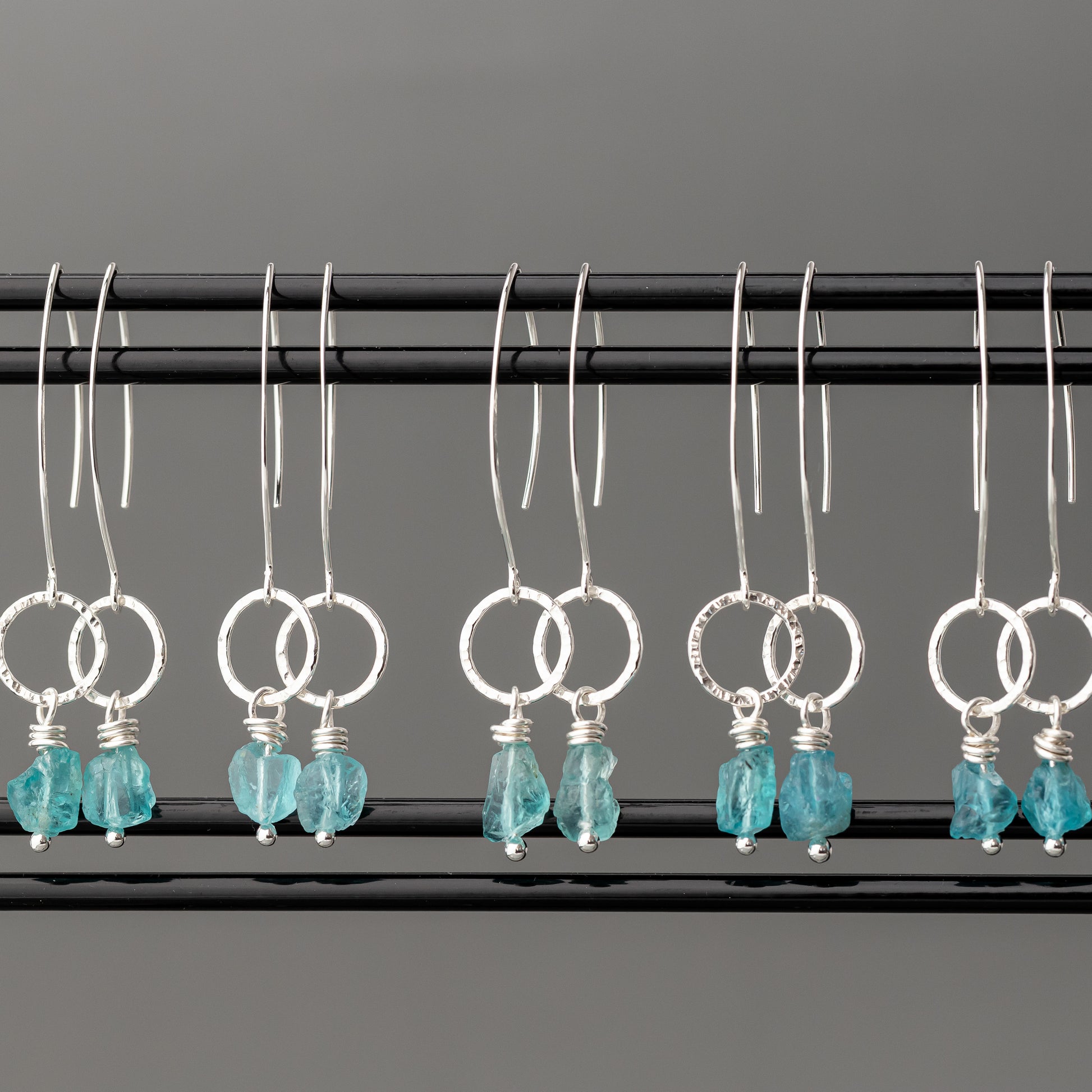 Pair of unique handmade sterling silver earrings with turquoise stones on a gray background