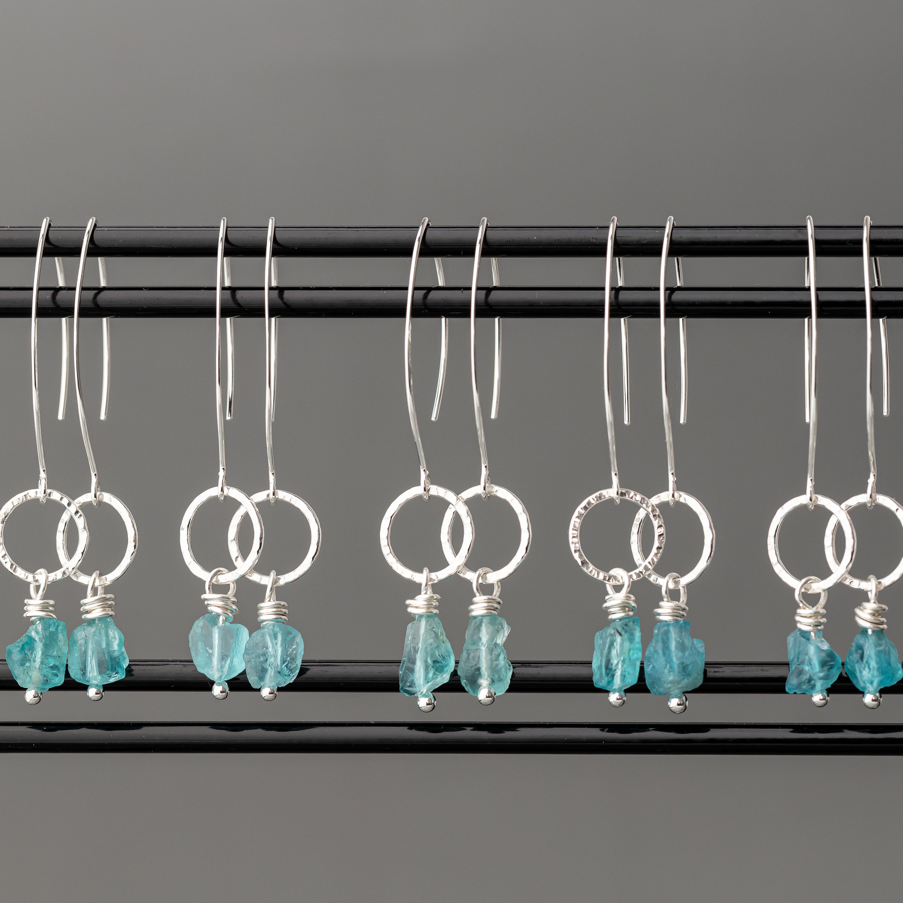 Pair of unique handmade sterling silver earrings with turquoise stones on a gray background