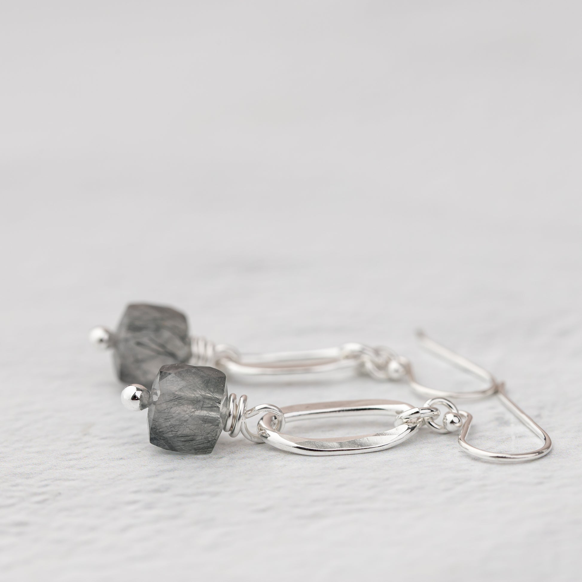 Side view of a pair of gemstone cube earrings handmade with sterling silver and natural stones