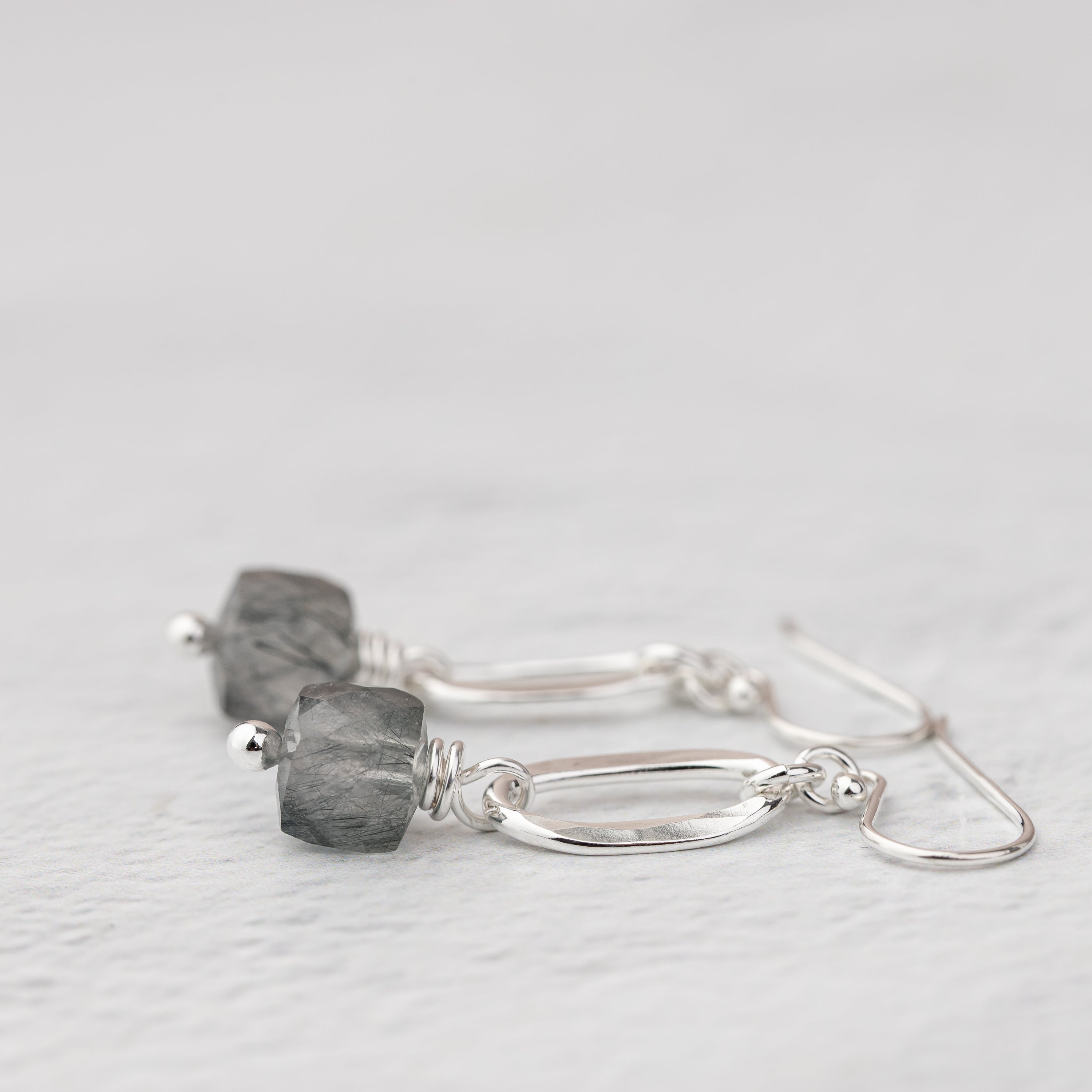 Side view of a pair of gemstone cube earrings handmade with sterling silver and natural stones