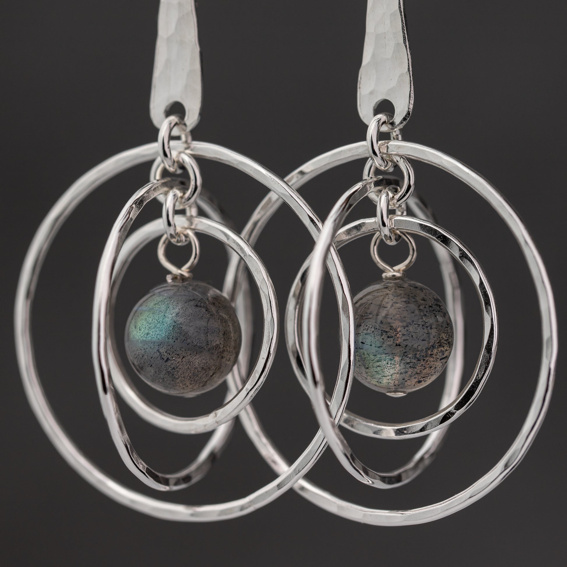 Silver hoop earrings with Labradorite stones on a black background