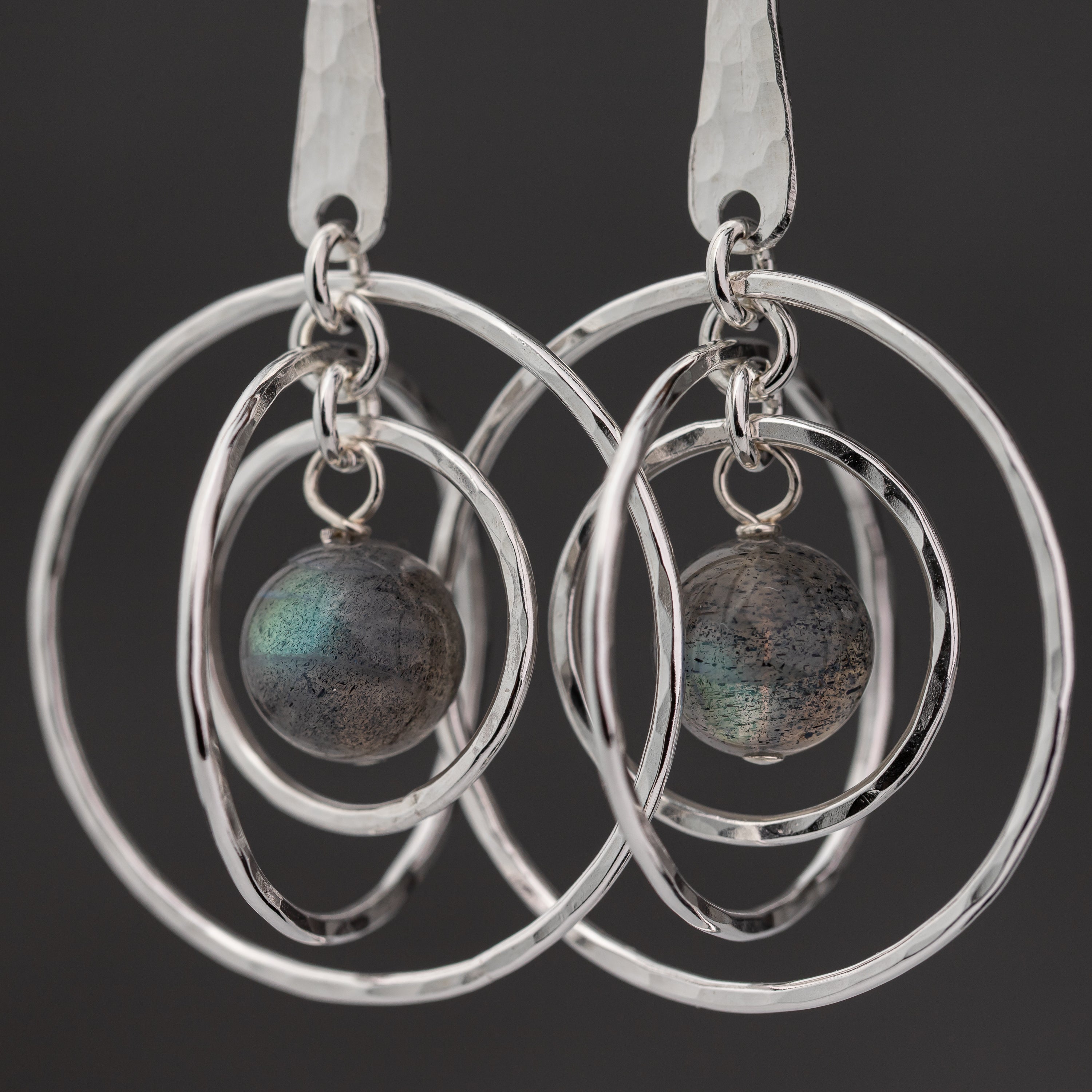 Silver hoop earrings with Labradorite stones on a black background