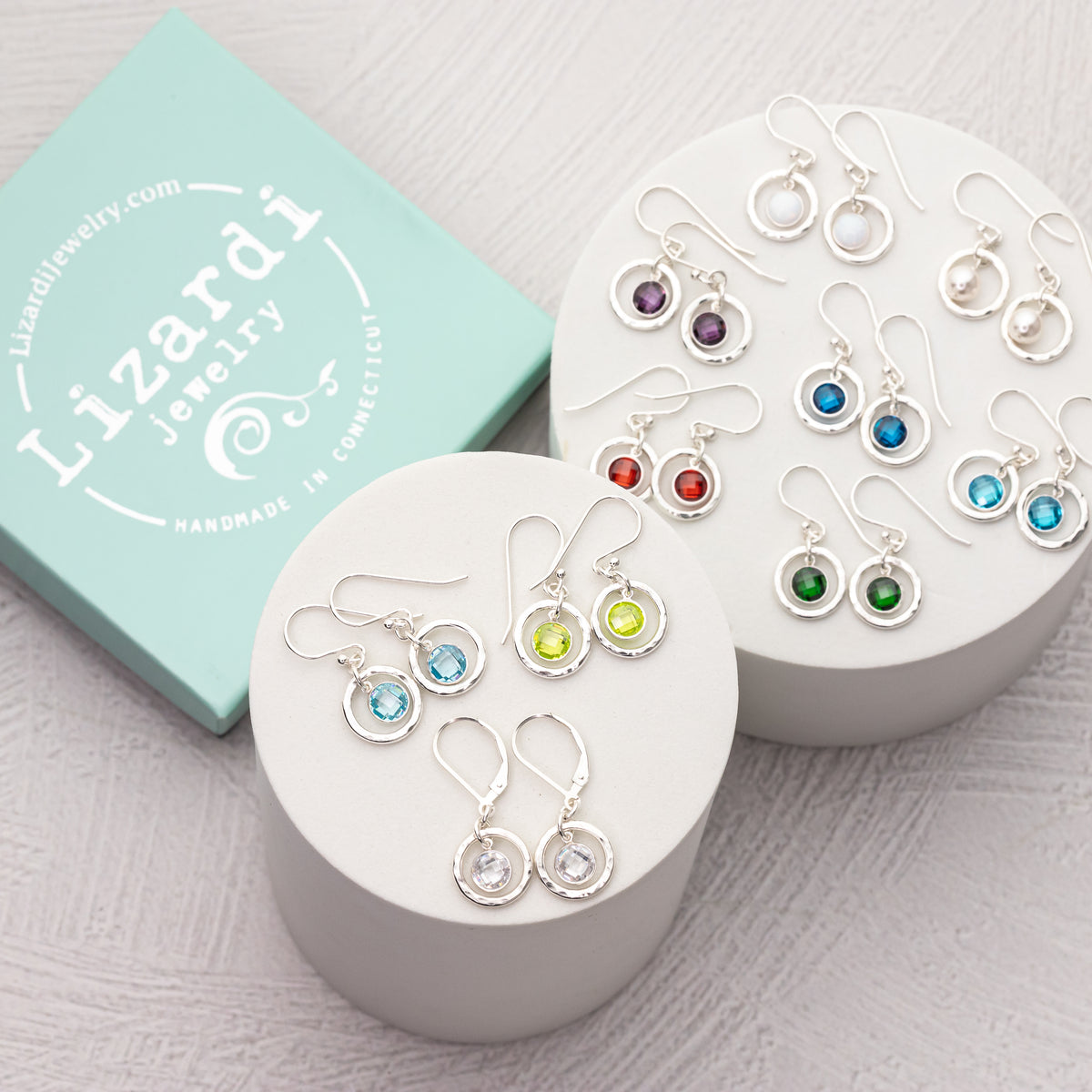 Handmade custom birthstone earrings shown in all the different colors they features sparkling czs in handmade hammered sterling silver frames.  
