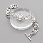 handmade sterling silver chain toggle bracelet with a coin pearl center shown on a gray background