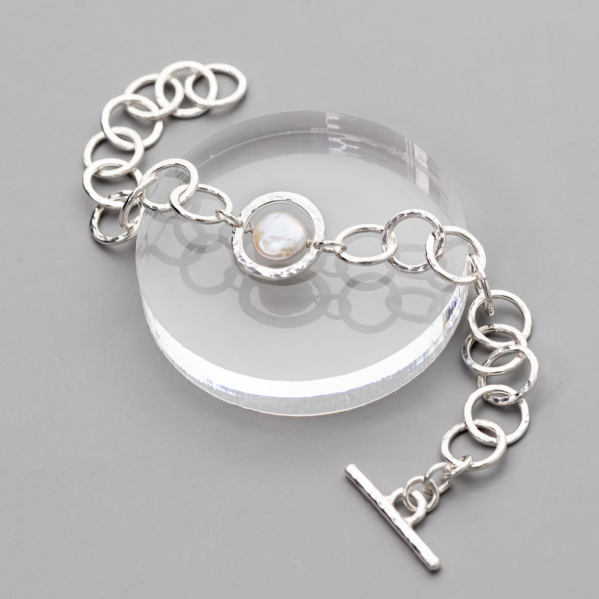 handmade sterling silver chain toggle bracelet with a coin pearl center shown on a gray background