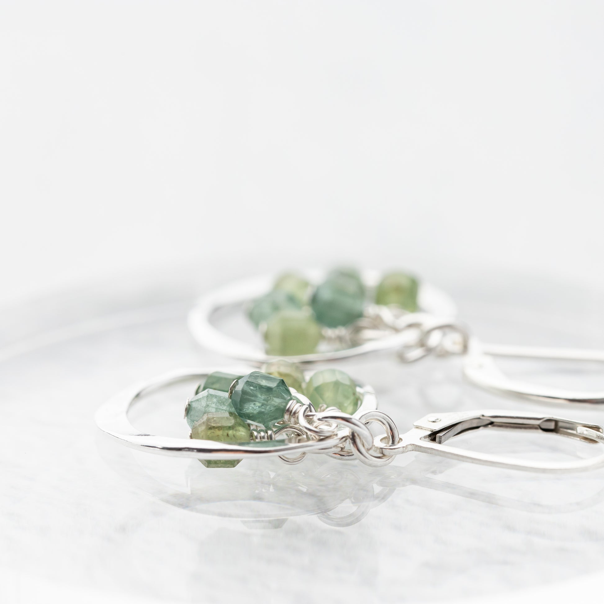 Green gemstone dangle earrings on a white background