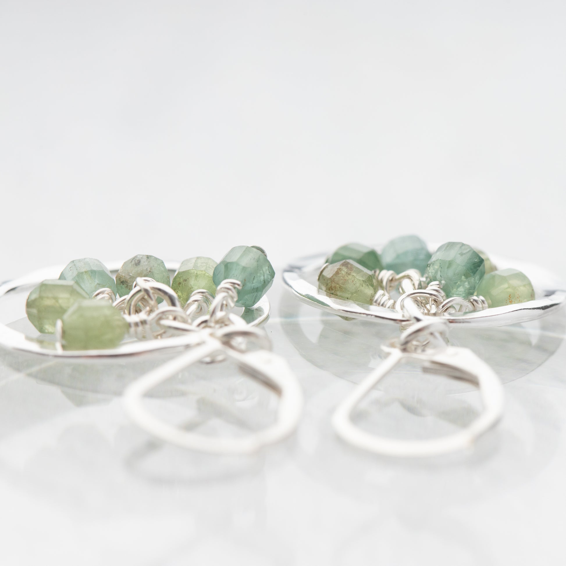 Pair of earrings with green gemstones on a white background
