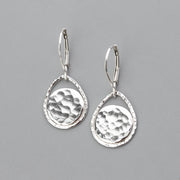 Handmade sterling silver lever back earrings shown against a gray background. The dangle earrings feature hand hammer textured discs that are surrounded by an open teardrop shape to frame them beautifully. 