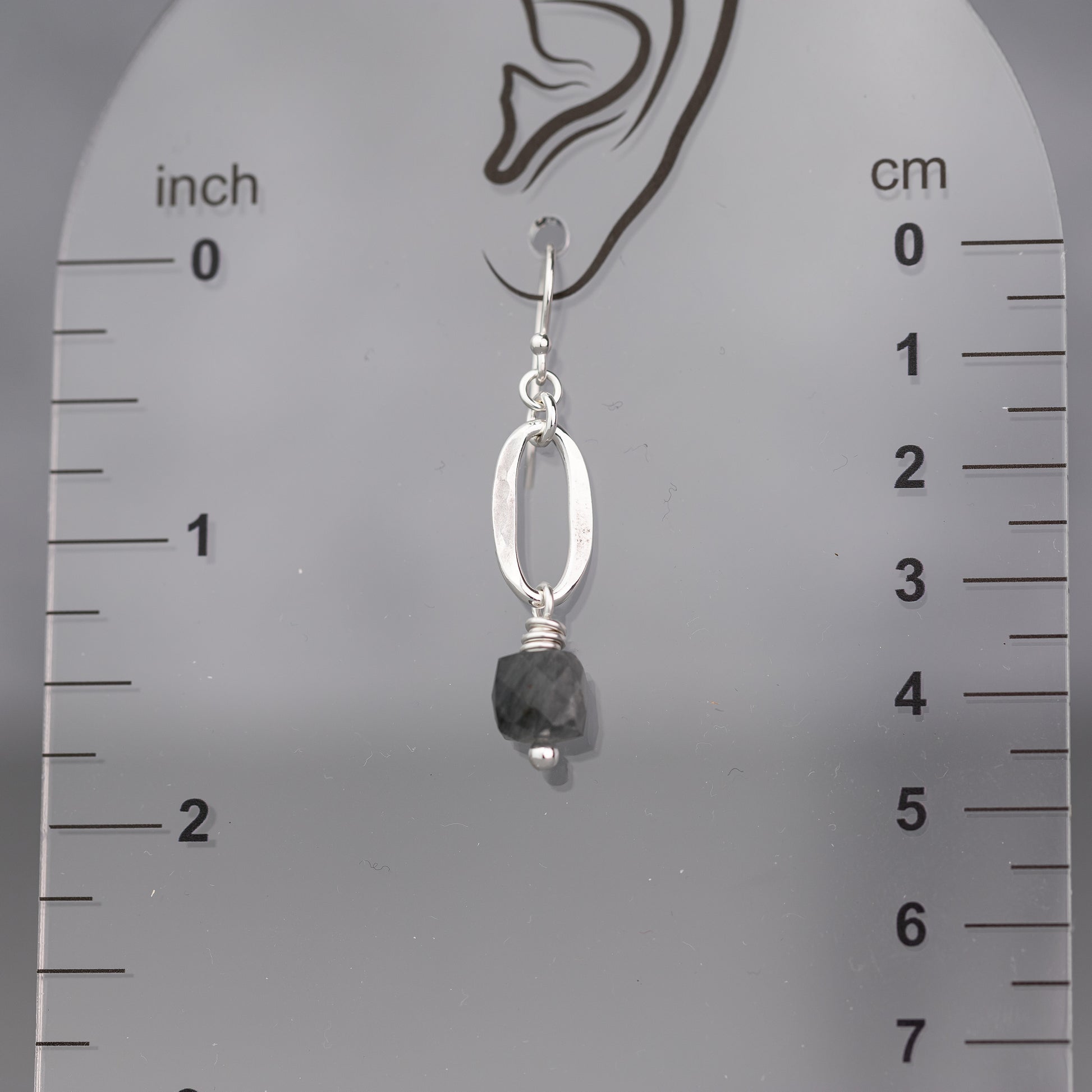 Silver earring with a quartz cube gemstone and sterling silver oval  on a ruler for scale