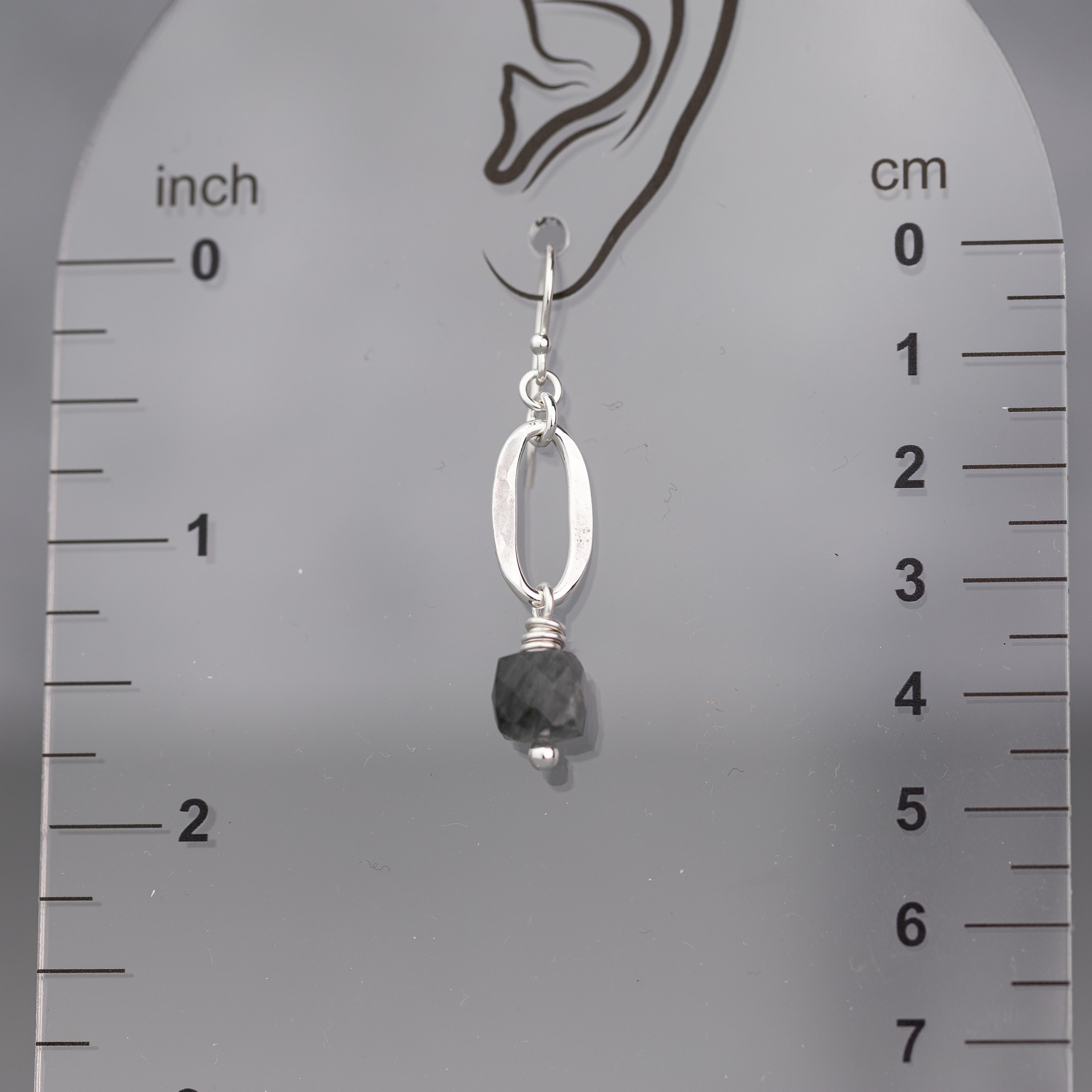 Silver earring with a quartz cube gemstone and sterling silver oval  on a ruler for scale