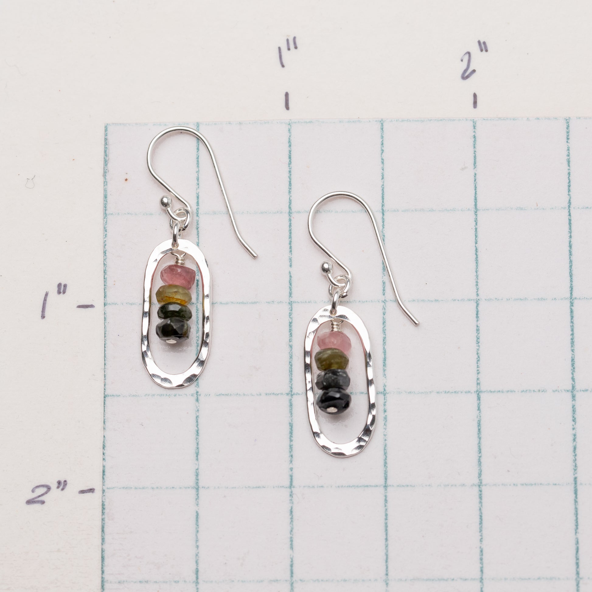 Pair of earrings with tourmaline gemstones on a ruler for scale