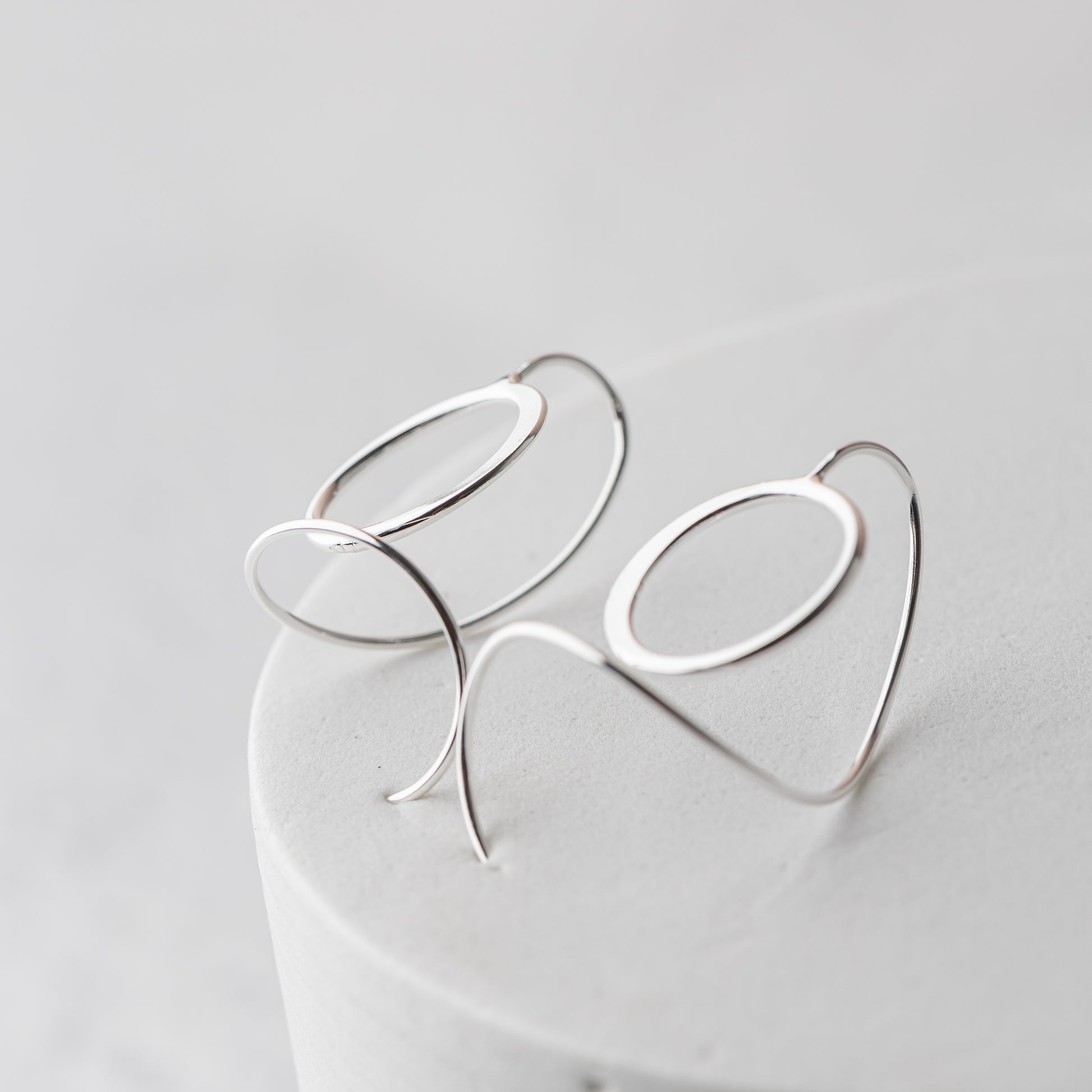 Silver circle earrings with a unique design on a light gray background