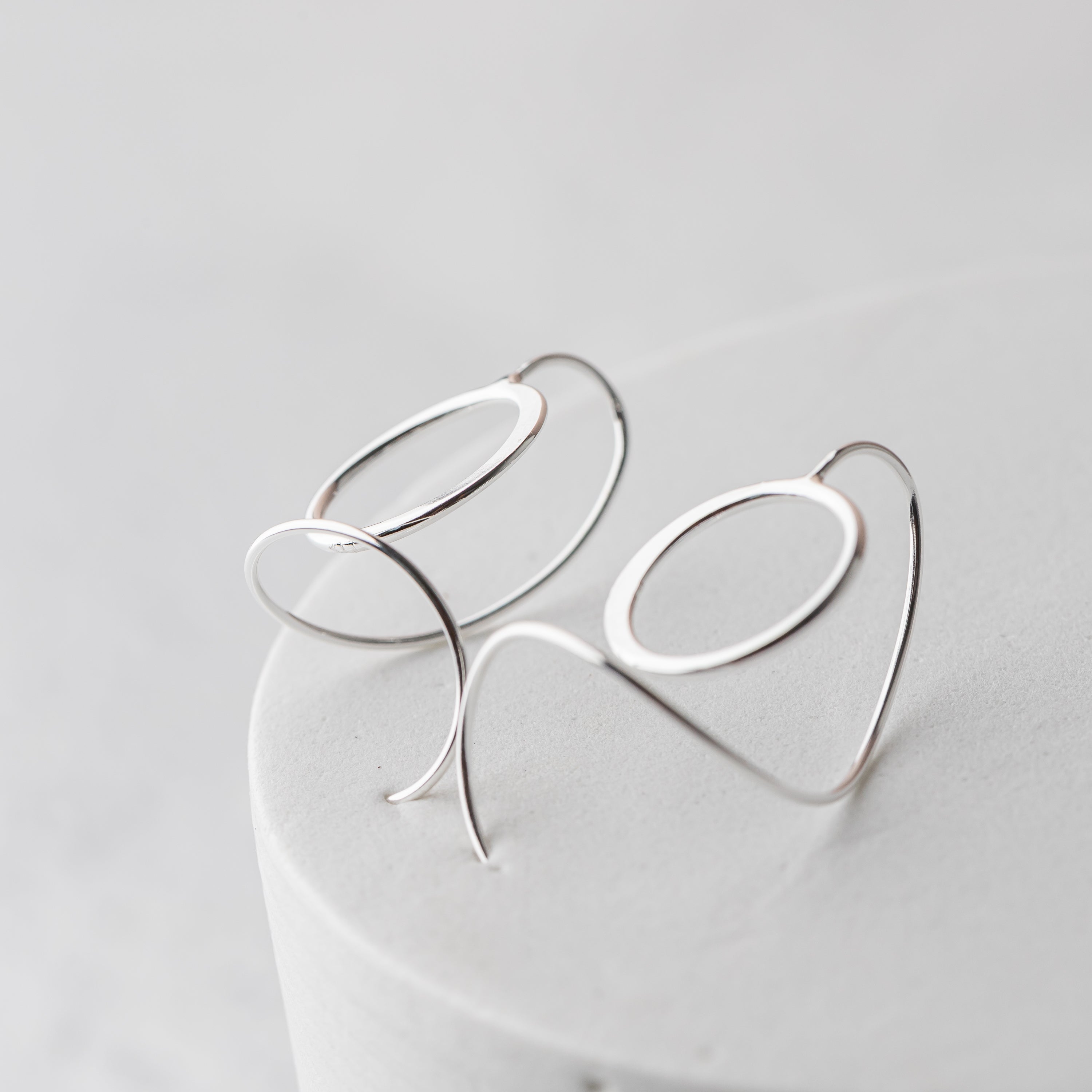 Silver circle earrings with a unique design on a light gray background