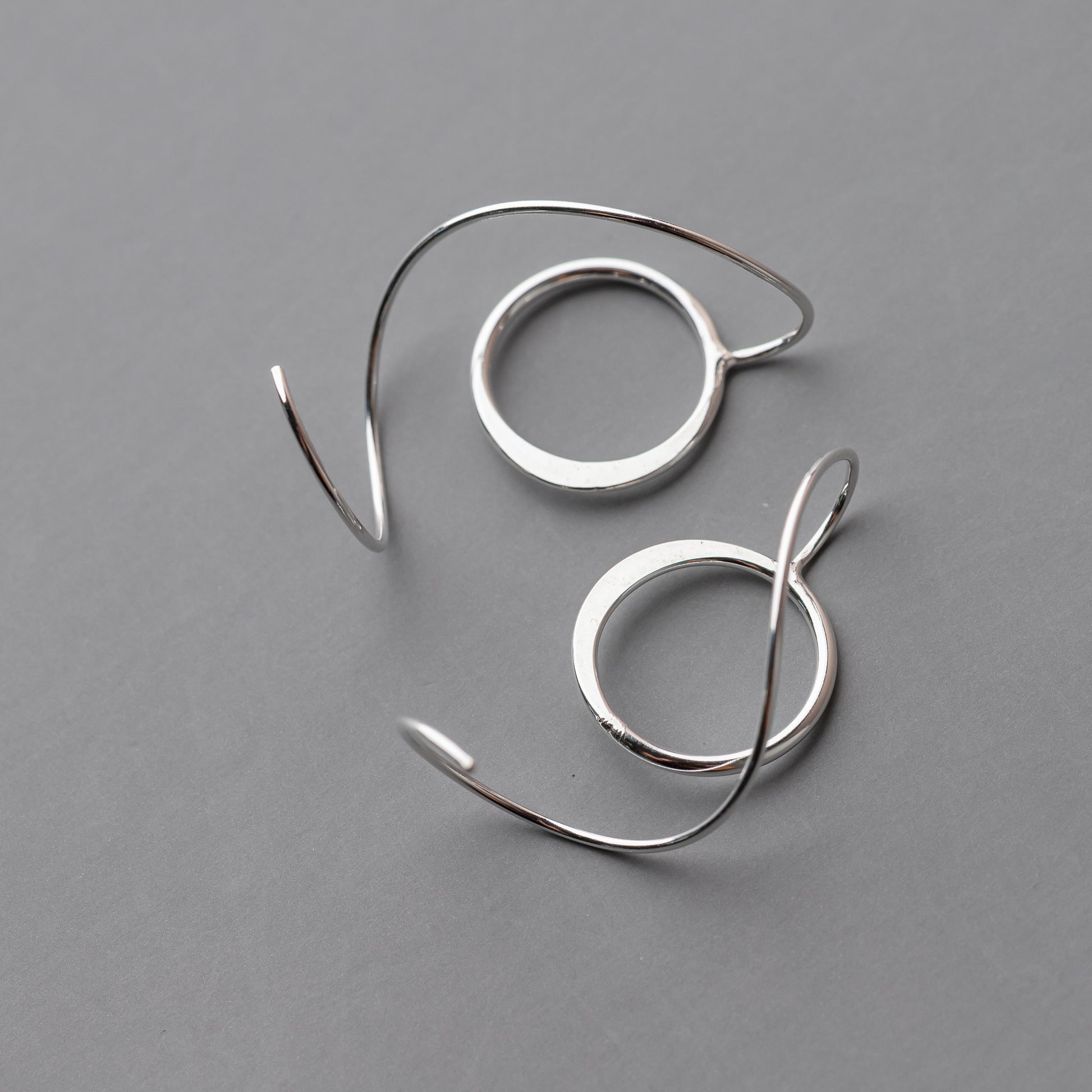 Pair of silver hoop threader earrings on a gray background