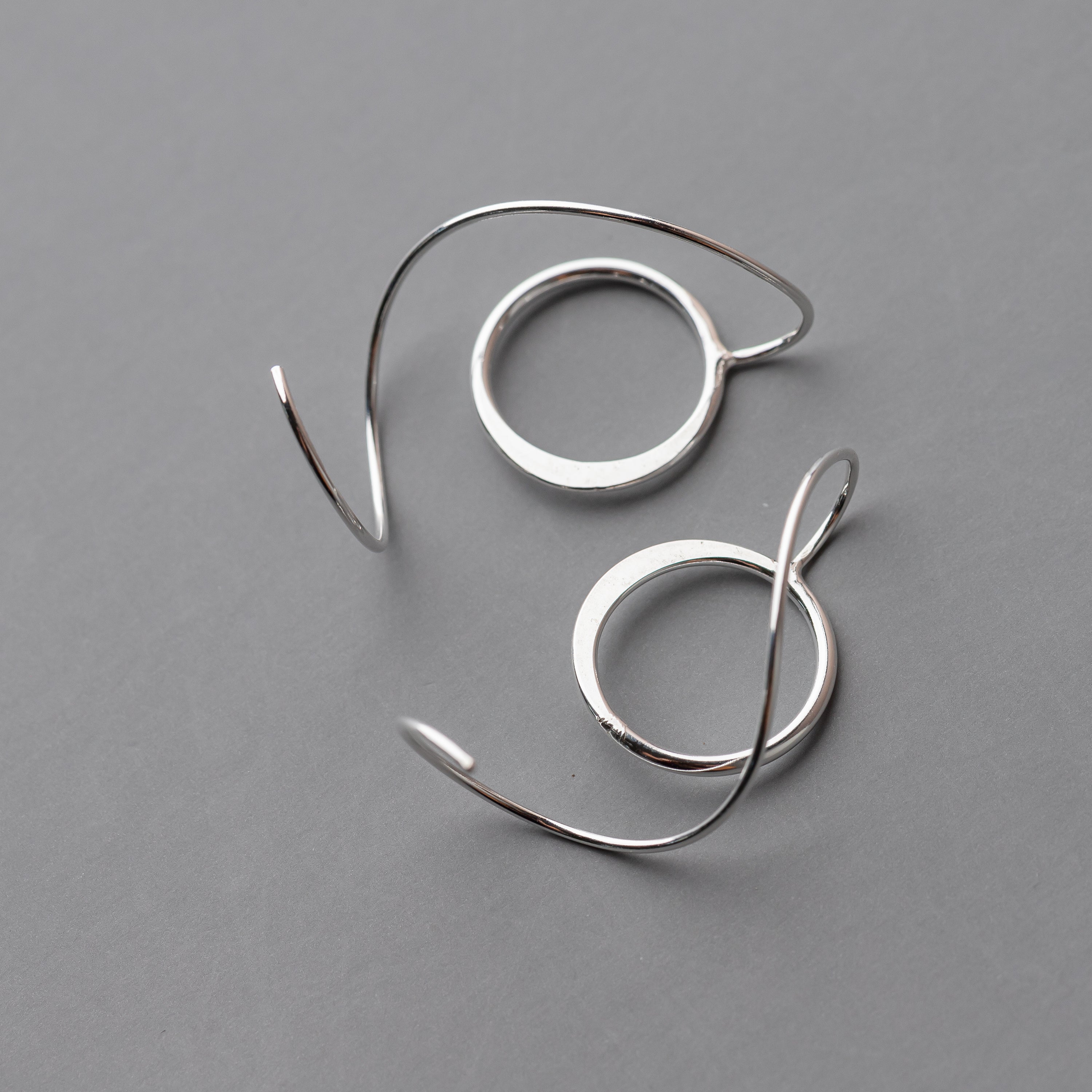 Pair of silver hoop threader earrings on a gray background