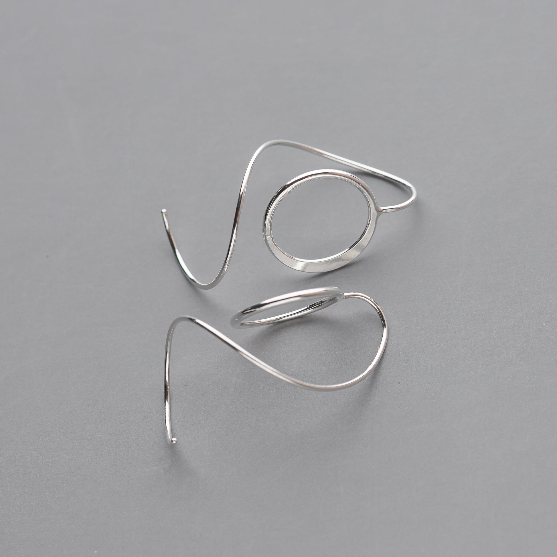 Pair of silver spiral earrings on a gray background