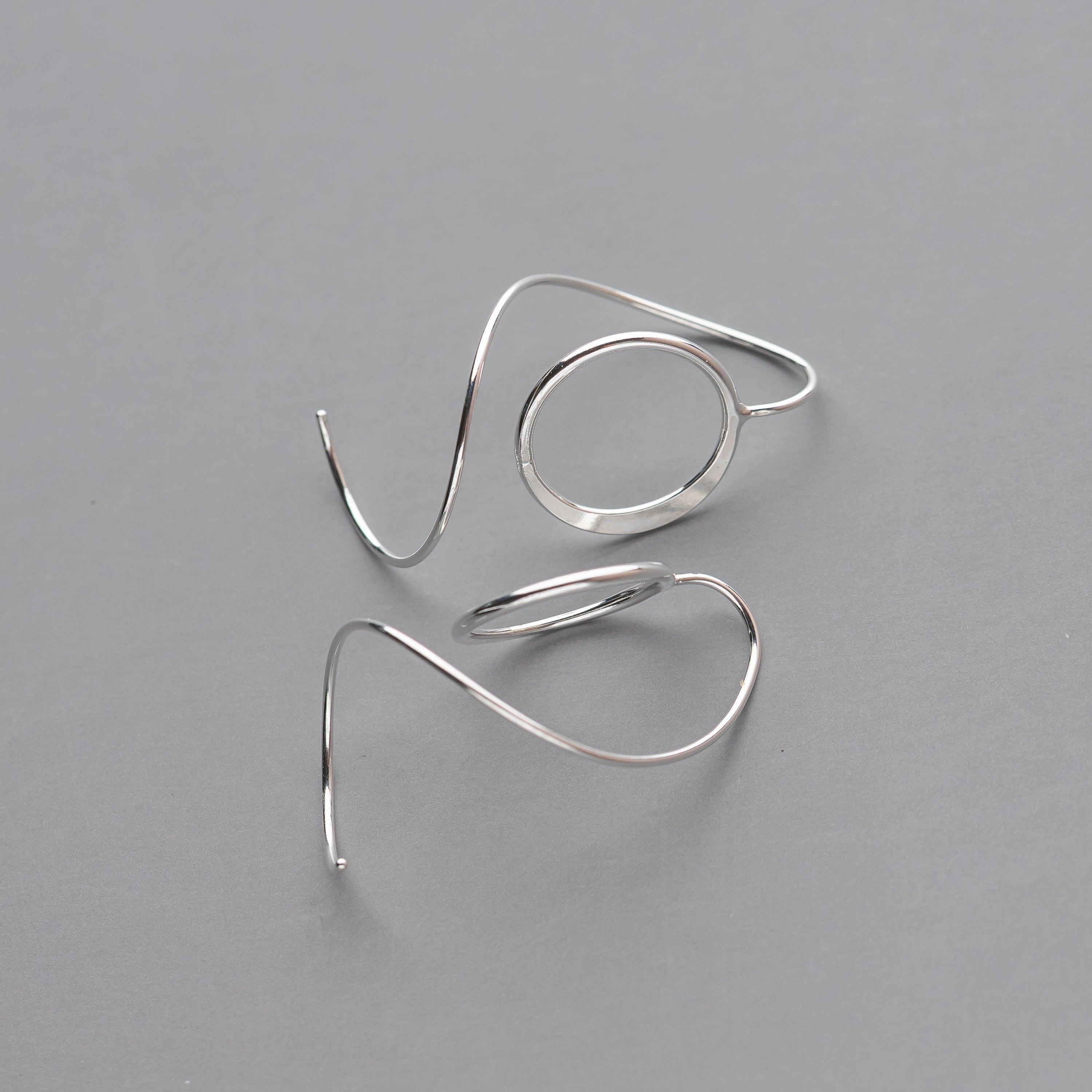 Pair of silver spiral earrings on a gray background