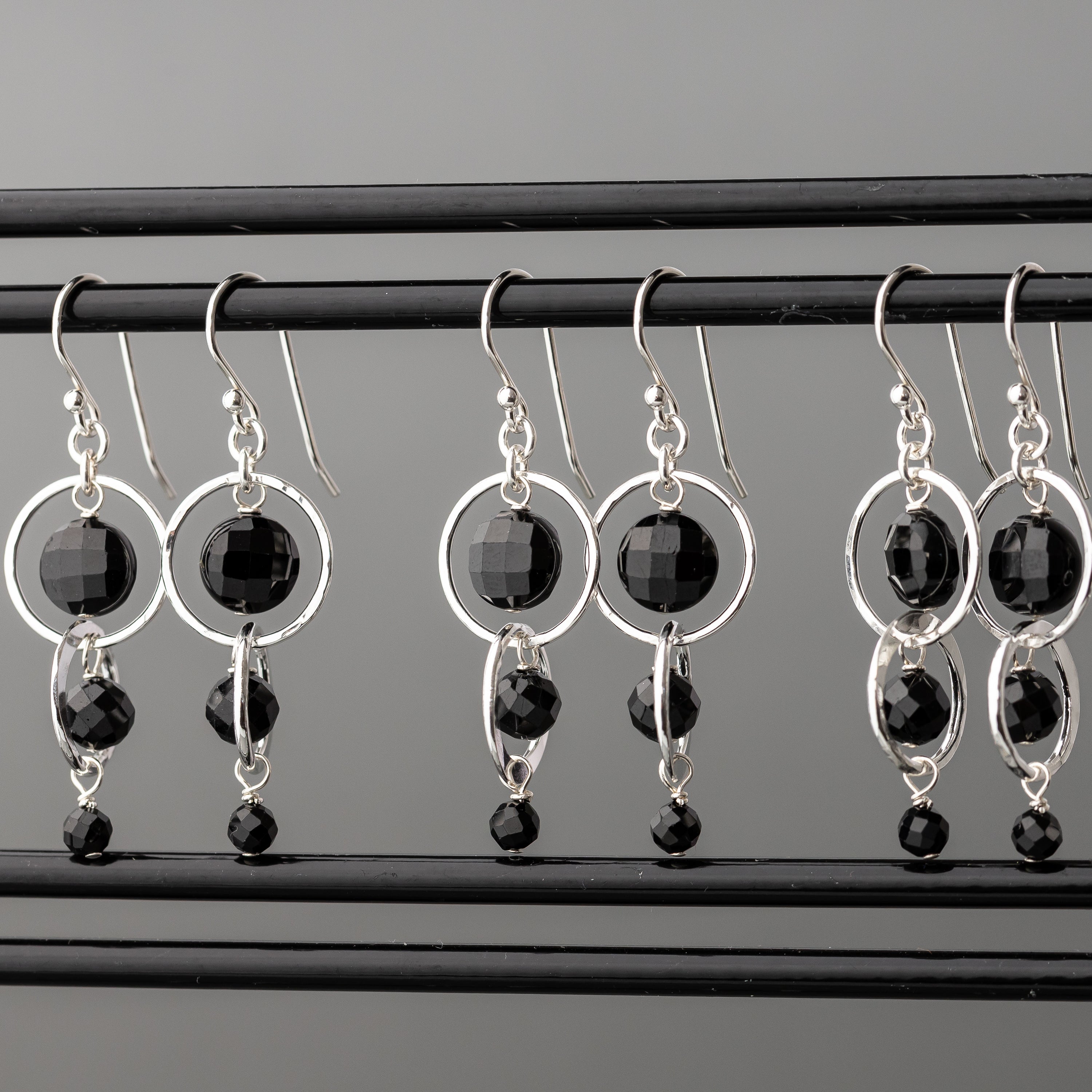 Pairs of black tourmaline and sterling silver dangle earrings shown hanging together
