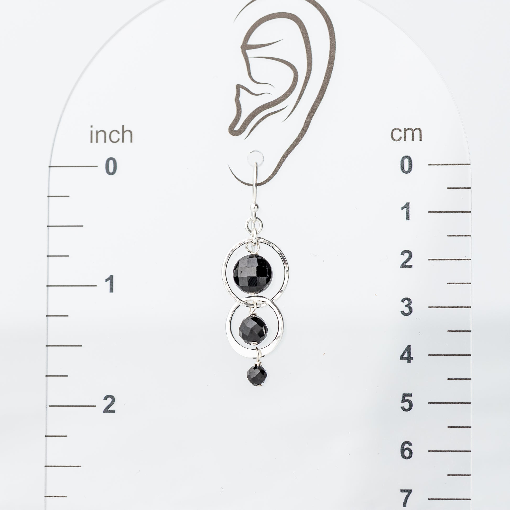 sterling silver handmade earring displayed on an ear with a measurement scale in inches and centimeters.