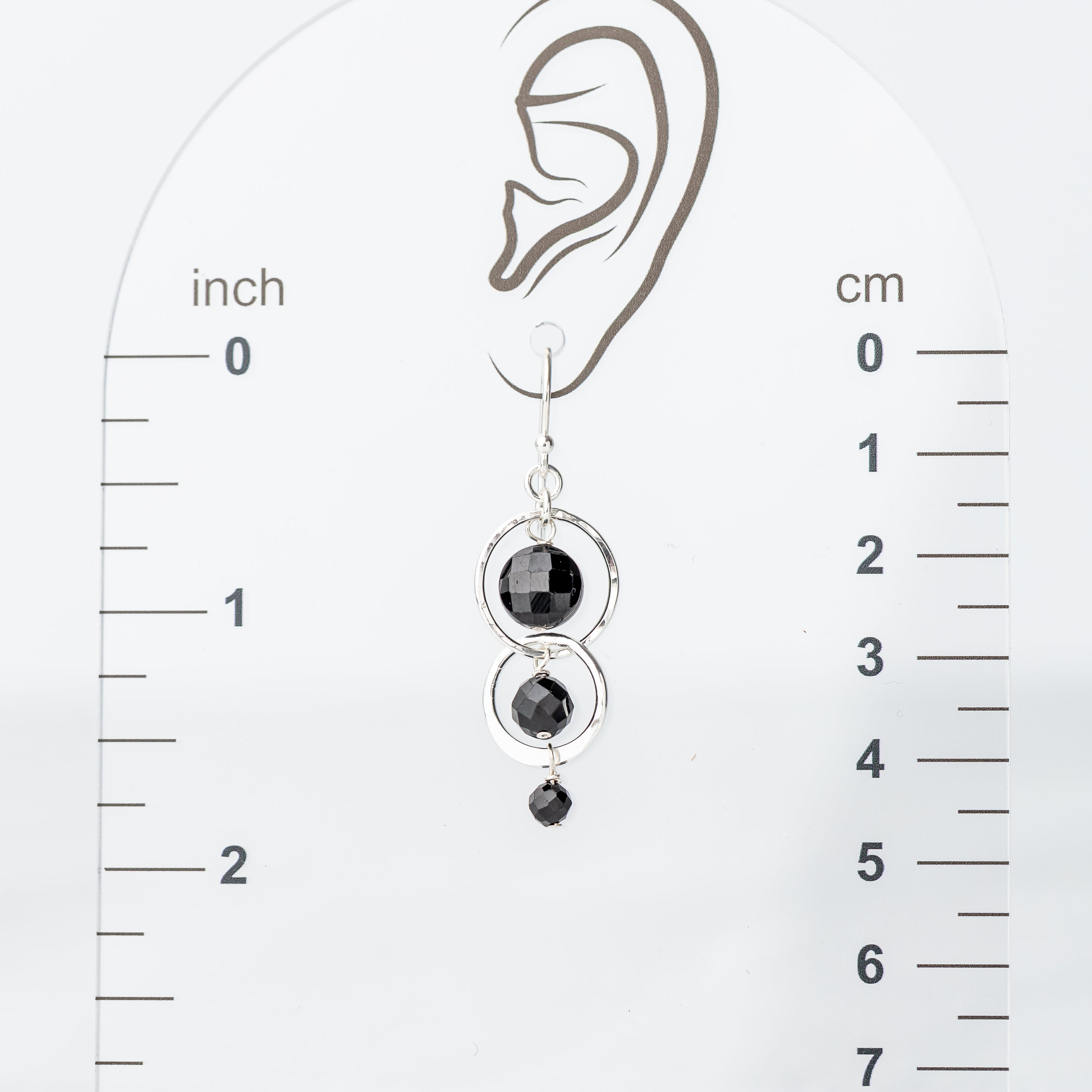 sterling silver handmade earring displayed on an ear with a measurement scale in inches and centimeters.