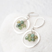 Sterling silver earrings with blue green apatite gemstones on a white background