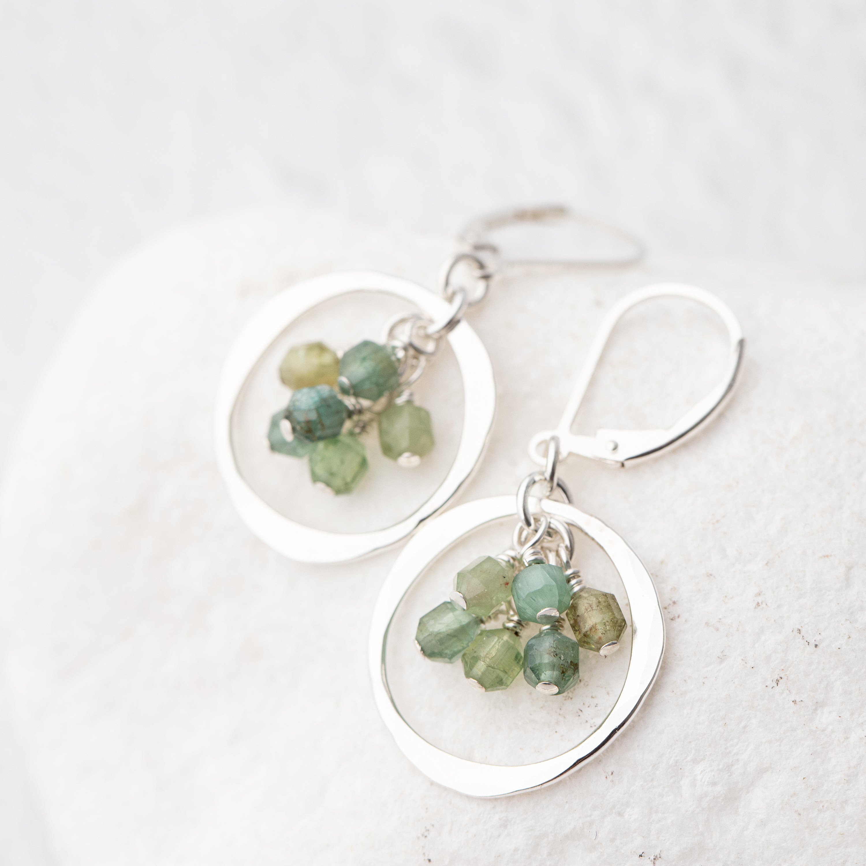 Sterling silver earrings with blue green apatite gemstones on a white background