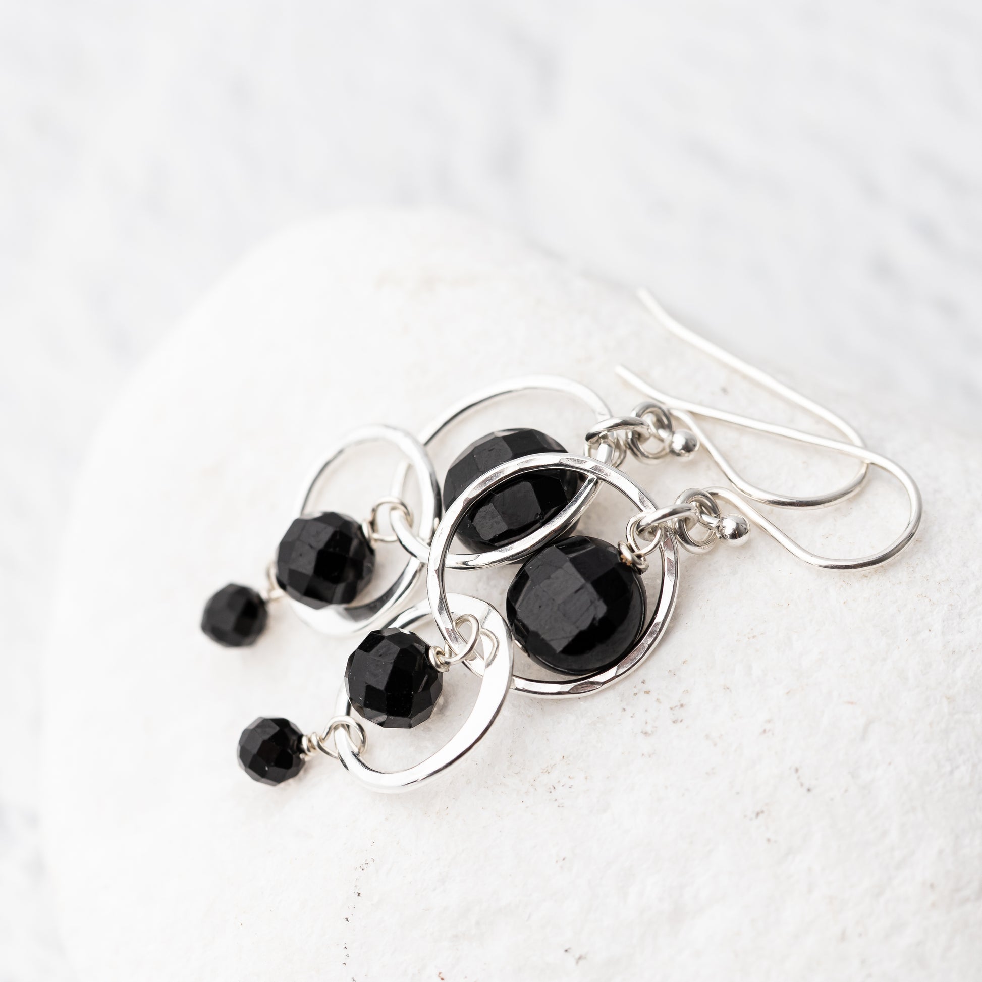 Black tourmaline and hammered sterling silver handmade earrings on a white background