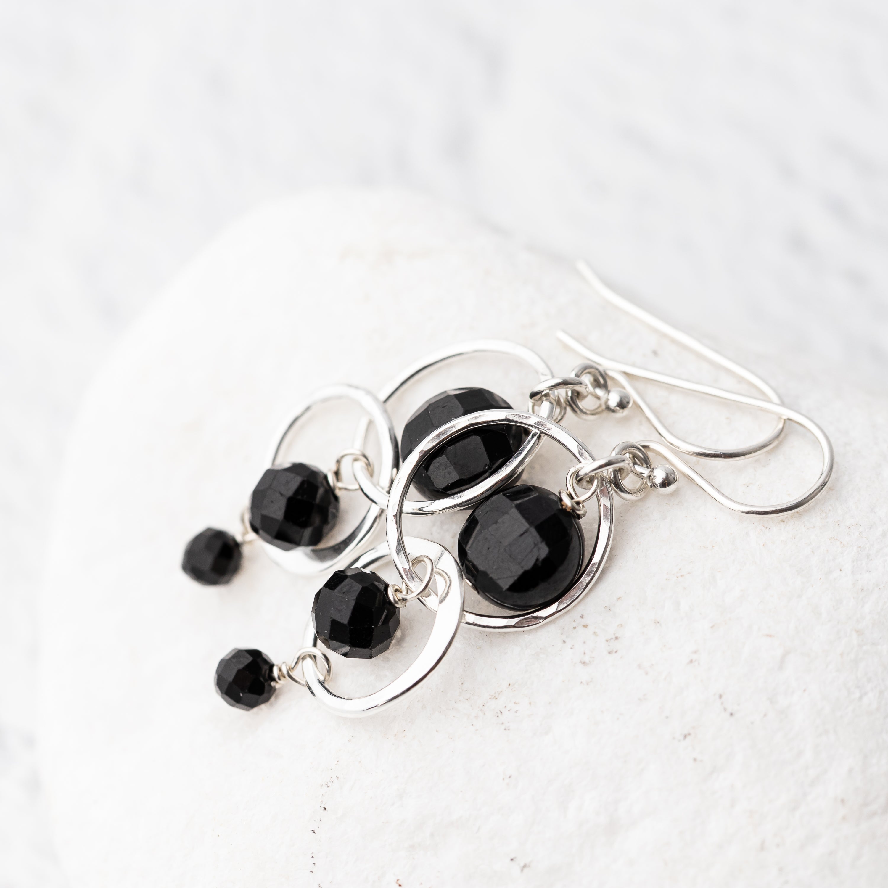 Black tourmaline and hammered sterling silver handmade earrings on a white background